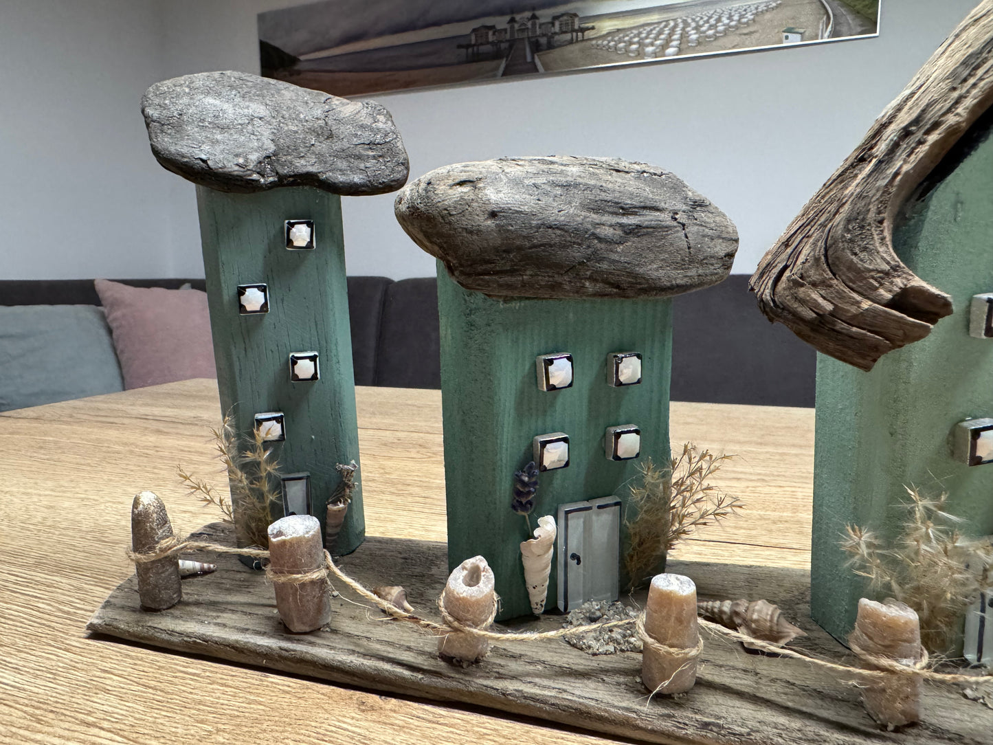 Detailbild der Häuser und des Donnerkeil-Zauns mit Muscheln und Naturmaterialien.