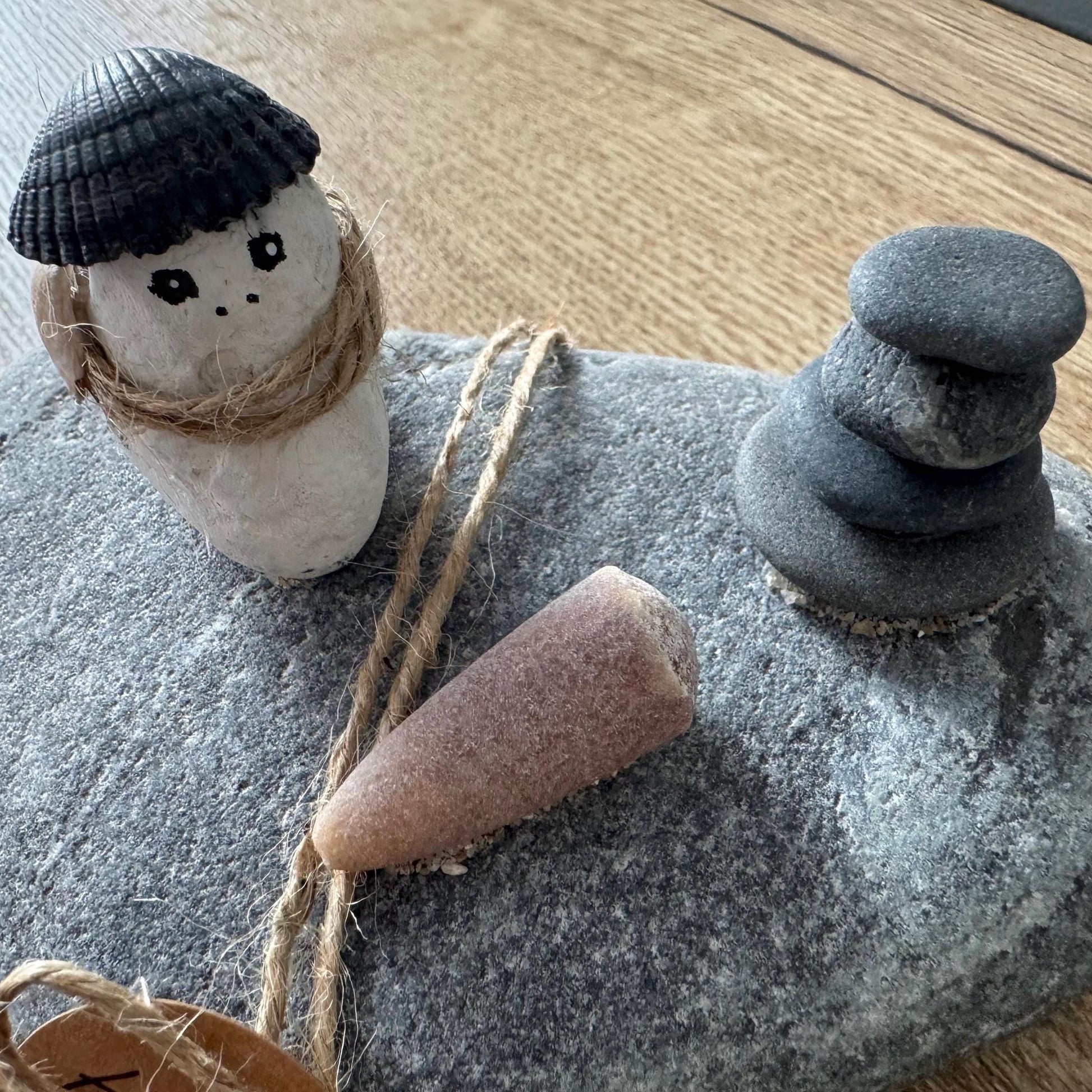 Detailaufnahme Steinfigur mit Muschel, Naturband und Donnerkeil aus echten Strandfunden