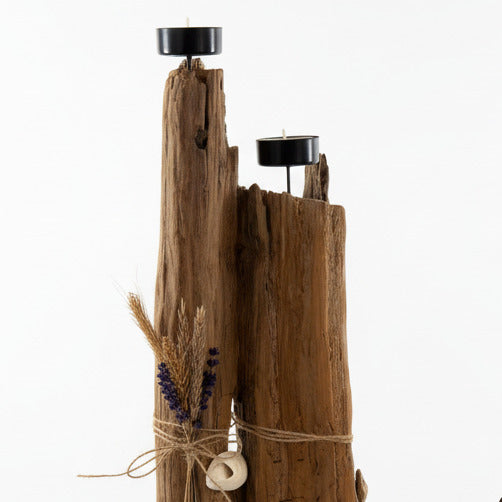 Ein rustikaler Kerzenhalter aus Holz mit zwei schwarzen Kerzenschalen. Der Halter ist mit Trockenblumen verziert.