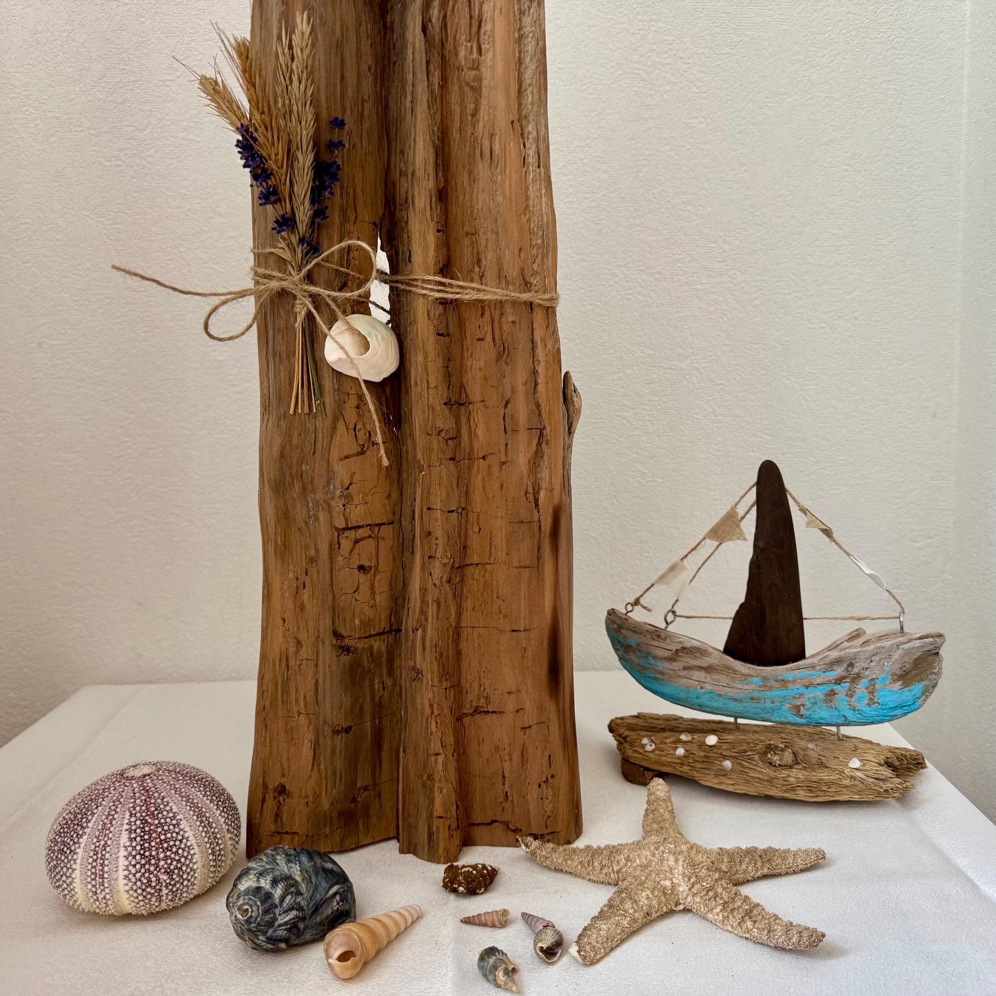 Eine Treibholzskulptur mit einem Bündel getrockneter Blumen und einer mit Schnur gebundenen Muschel von Treibholzzauber79