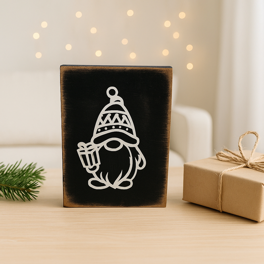 Rustikale Weihnachtsdeko aus Holz mit weißem Wichtel-Motiv auf schwarzem Holzblock, dekoriert im hellen skandinavischen Raum.