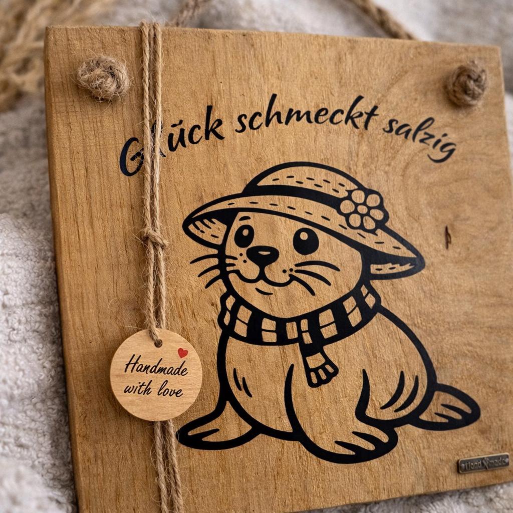 Maritime Wanddeko aus Eichenholz mit Robbe und Spruch Glück schmeckt salzig im skandinavischen Stil