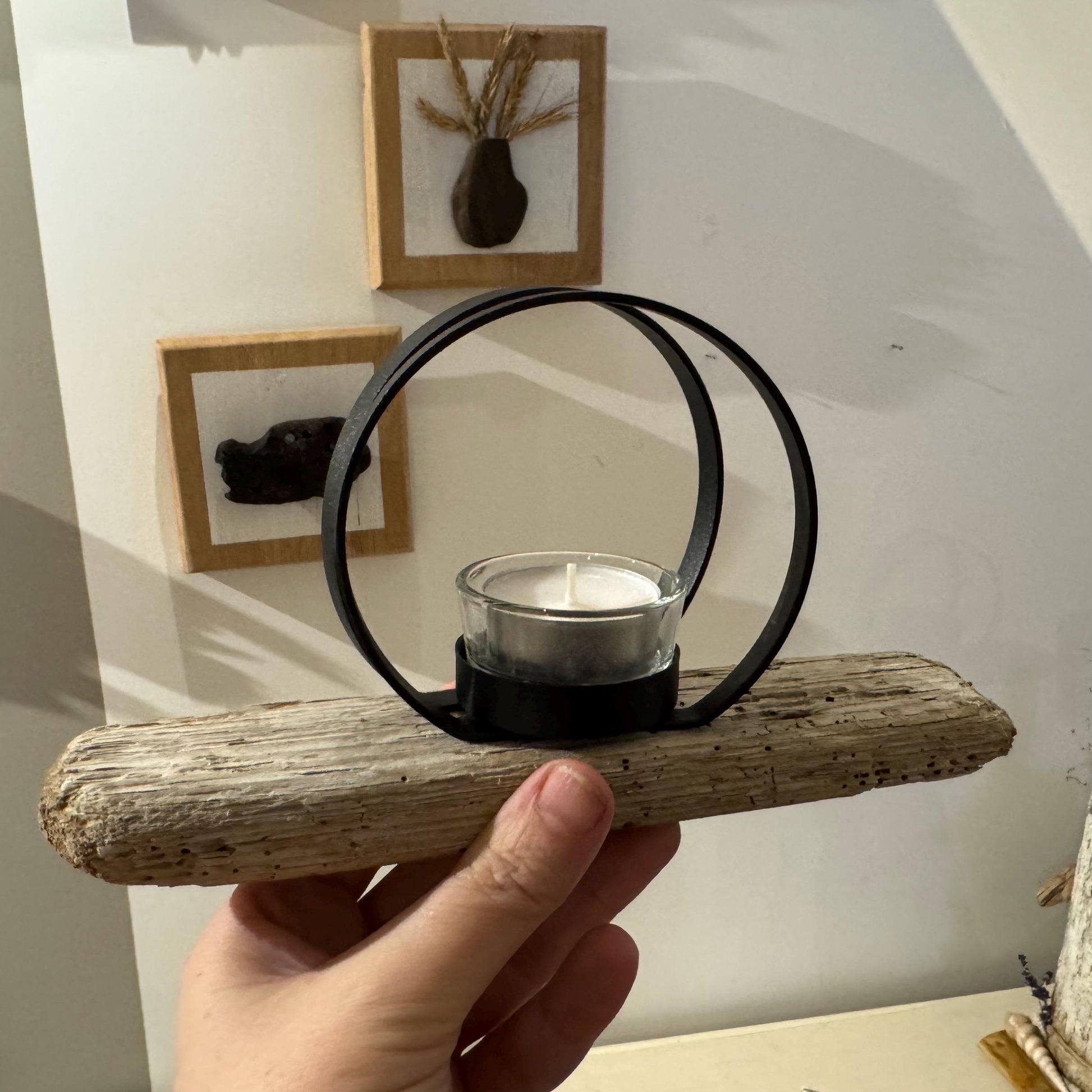 Hand hält Teelichthalter aus hellem Treibholz mit Metallring und Glas