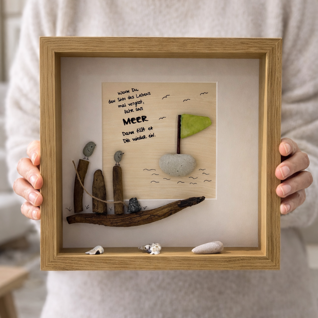 Hand hält Treibholz Bild mit Segelboot und Meer Spruch im Holzrahmen