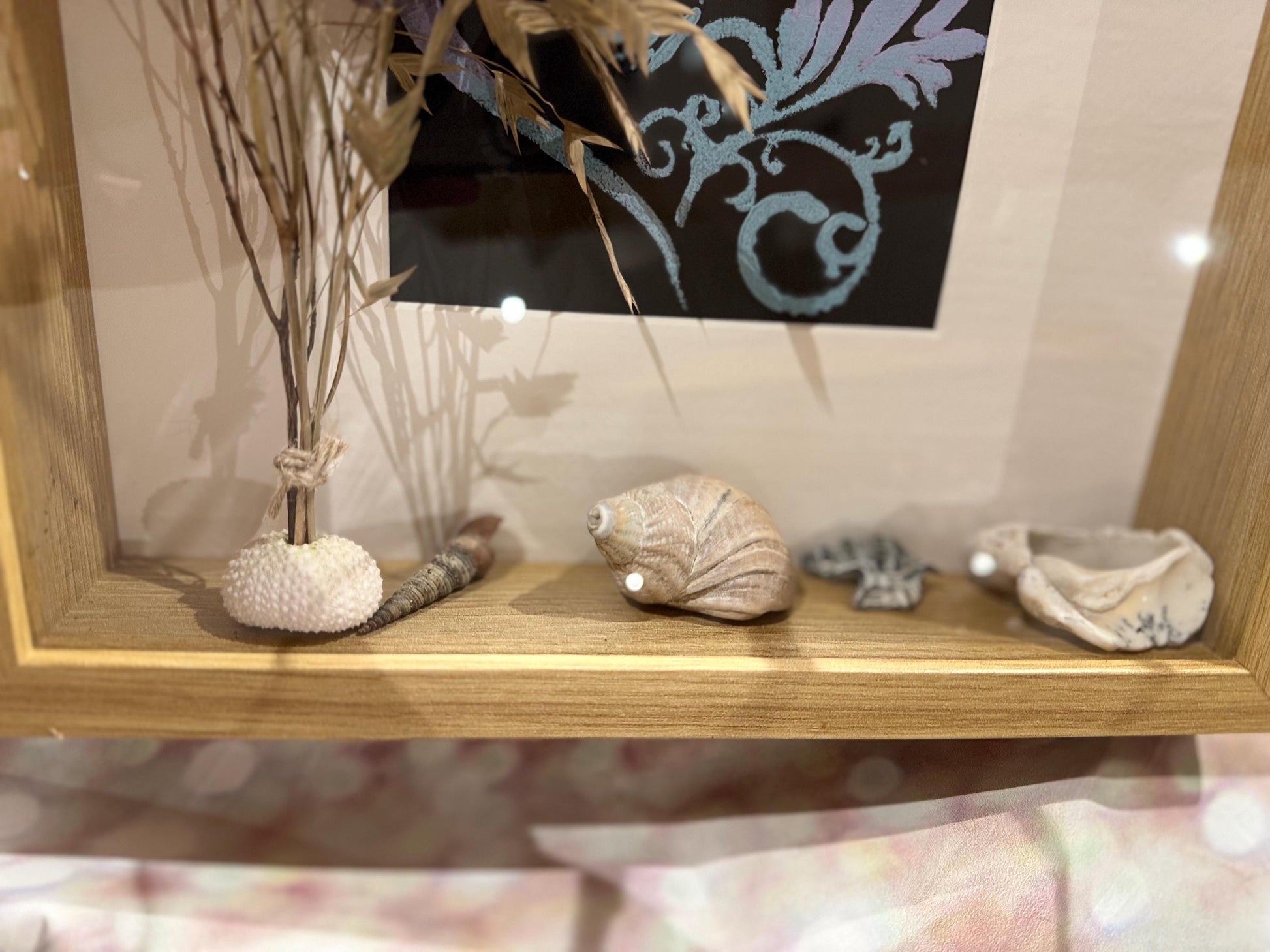 Detailaufnahme des personalisierten Bilderrahmens mit Muscheln, Strandsteinen und Trockenblumen im Holzrahmen