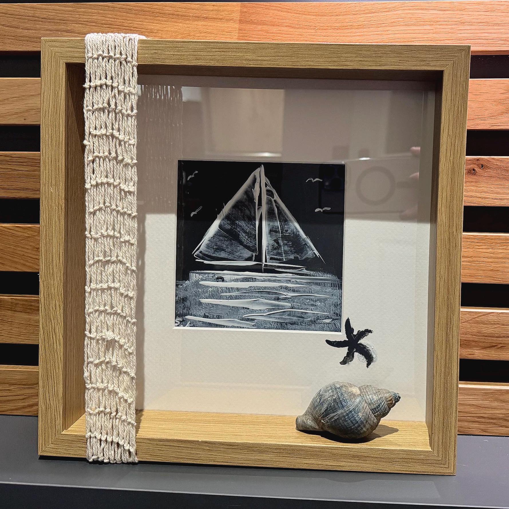 Gerahmtes nautisches Kunstwerk mit einem Schwarz-Weiß-Segelbootgemälde. Der Rahmen besteht aus hellem Holz.