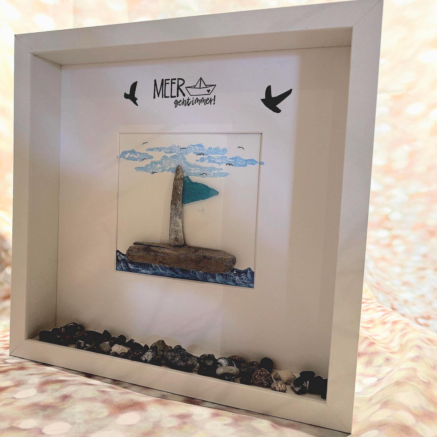 Gerahmtes Kunstwerk mit einem Segelboot aus Treibholz, blauem Segel und blauem Wasser. Das Kunstwerk mit MEER geht immer!