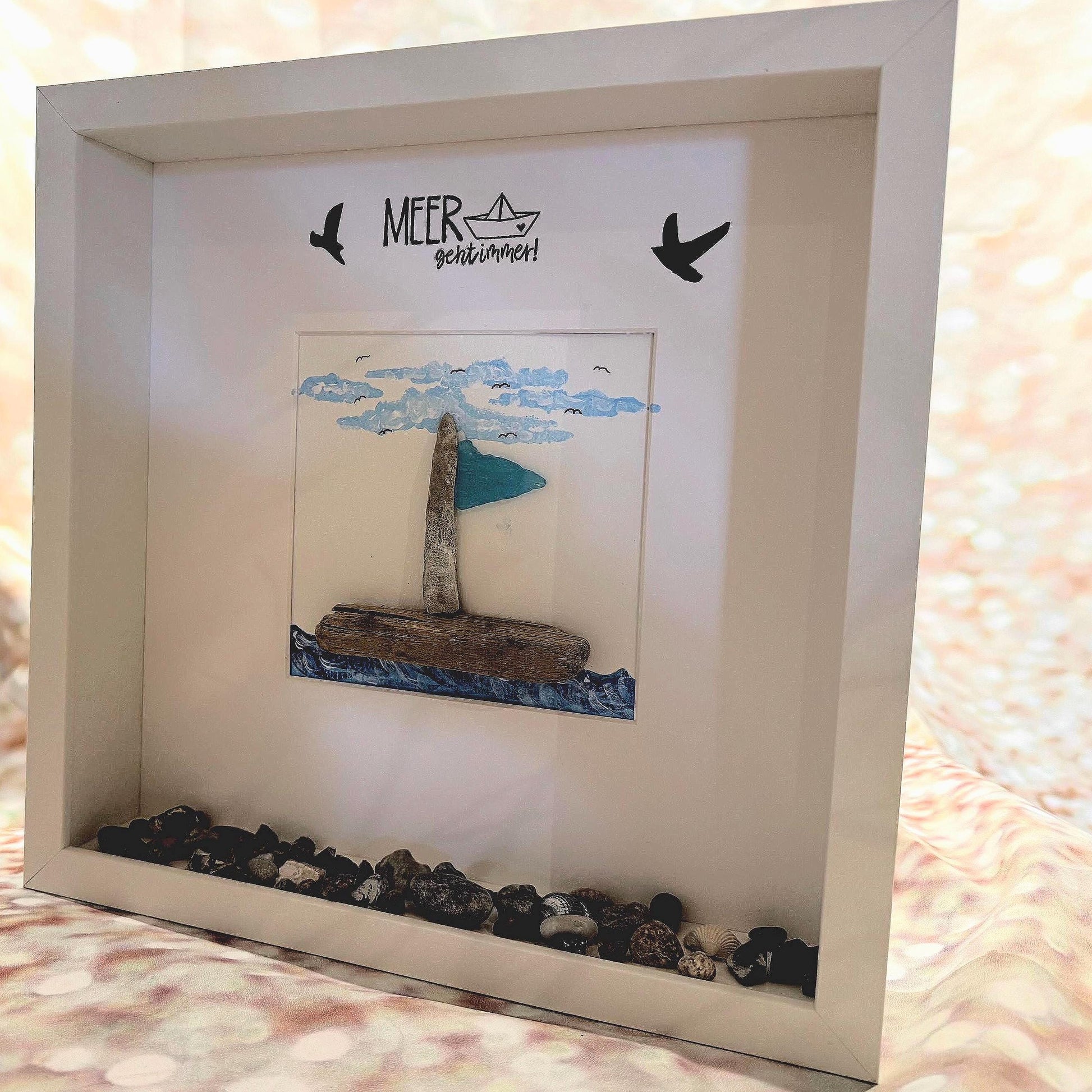 Gerahmtes Kunstwerk mit einem Segelboot aus Treibholz, blauem Segel und blauem Wasser. Das Kunstwerk mit MEER geht immer!