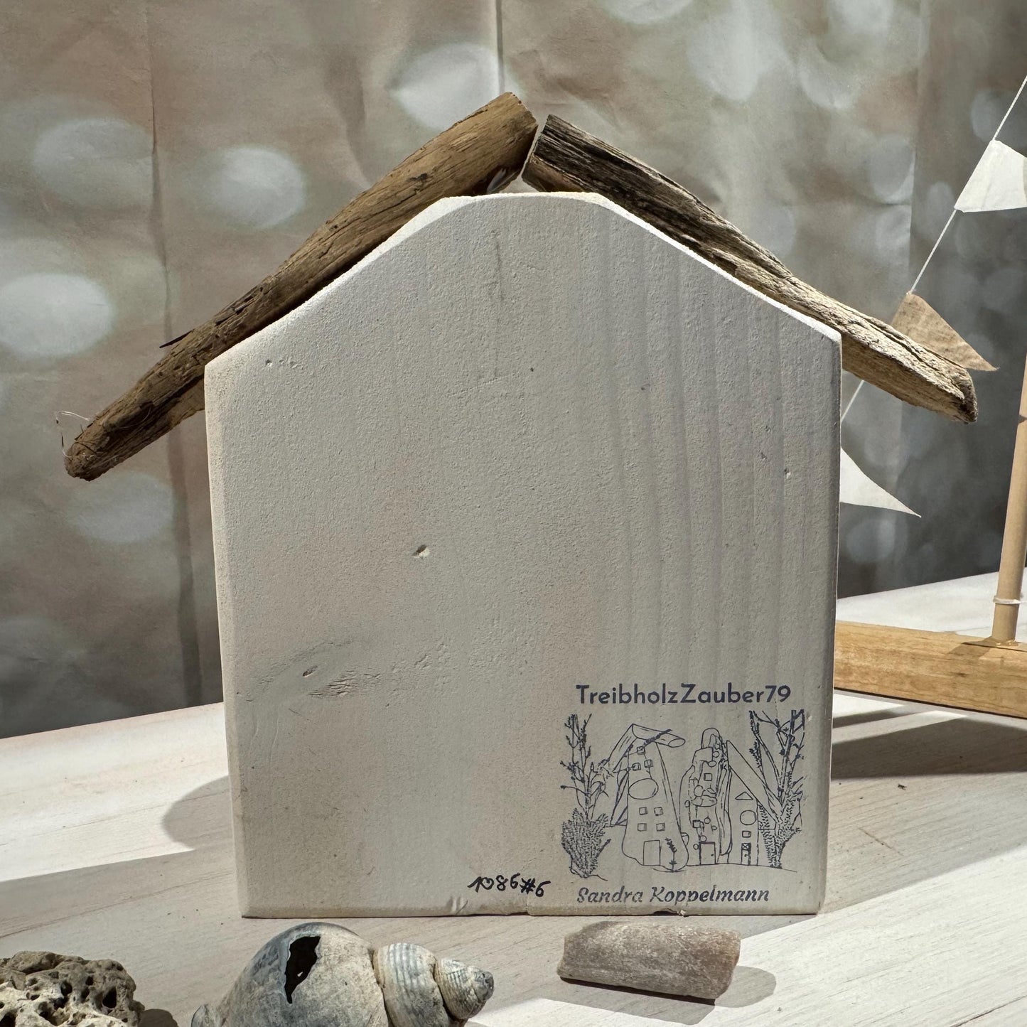 Rückseite des personalisierten Geburtshäuschens aus Holz mit schwarzen Baby Fußabdrücken, Treibholz Dach und Geburtsdaten