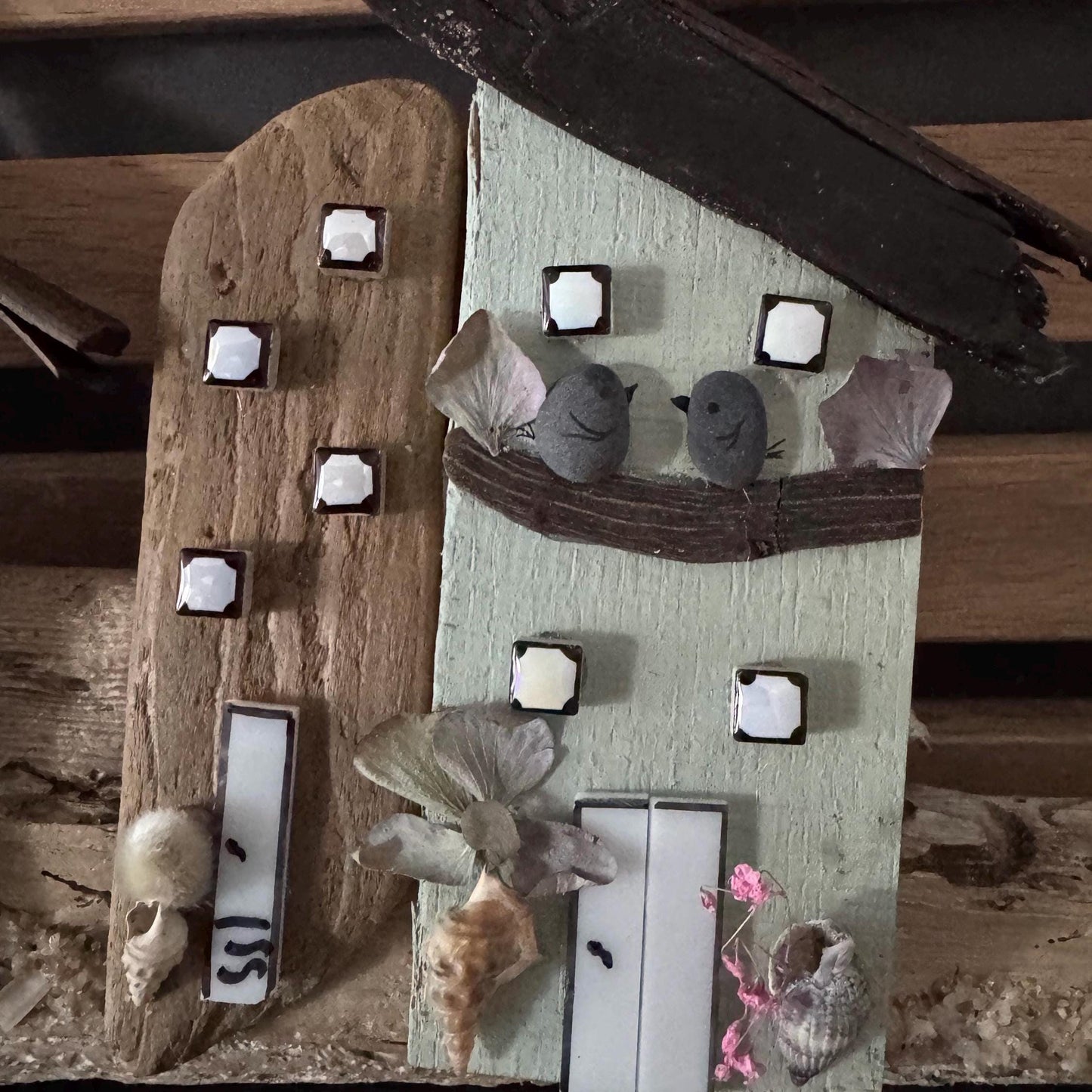 Ein rustikales, handgefertigtes Holzhaus mit hellgrünen und braunen Farbtönen.  Das Dach ist aus dunklem Holz.