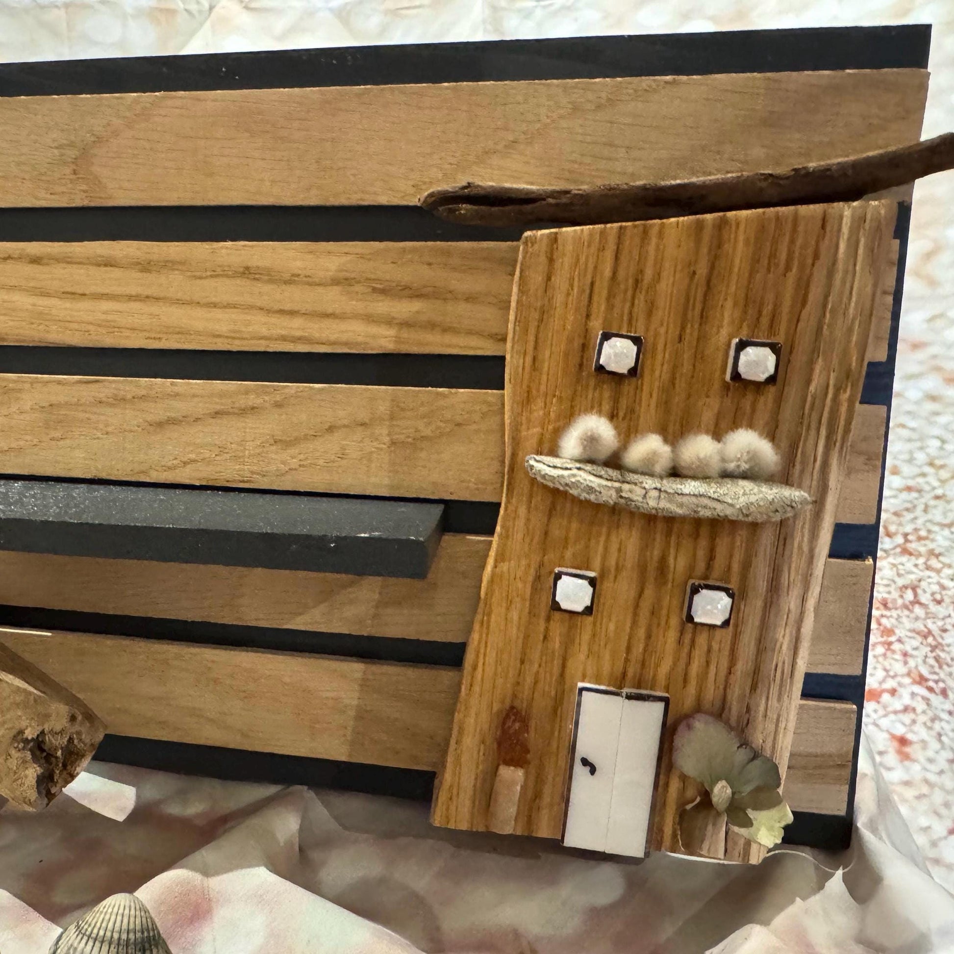 Detailaufnahme des kleinen Holzhauses mit maritimen Elementen auf dem Wandpaneel von Treibholzzauber79