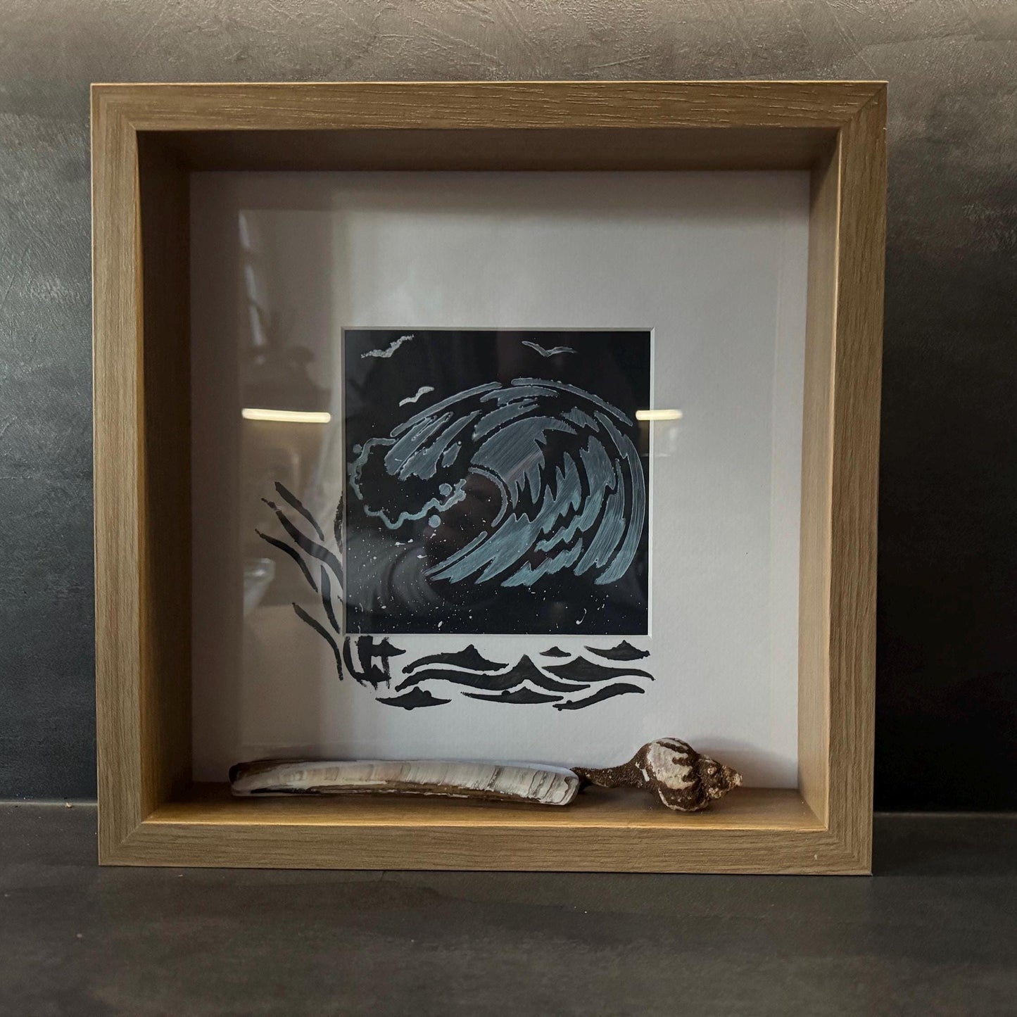 Gerahmtes Kunstwerk mit einem stilisierten Wellenmuster in Grau- und Weißtönen auf schwarzem Hintergrund