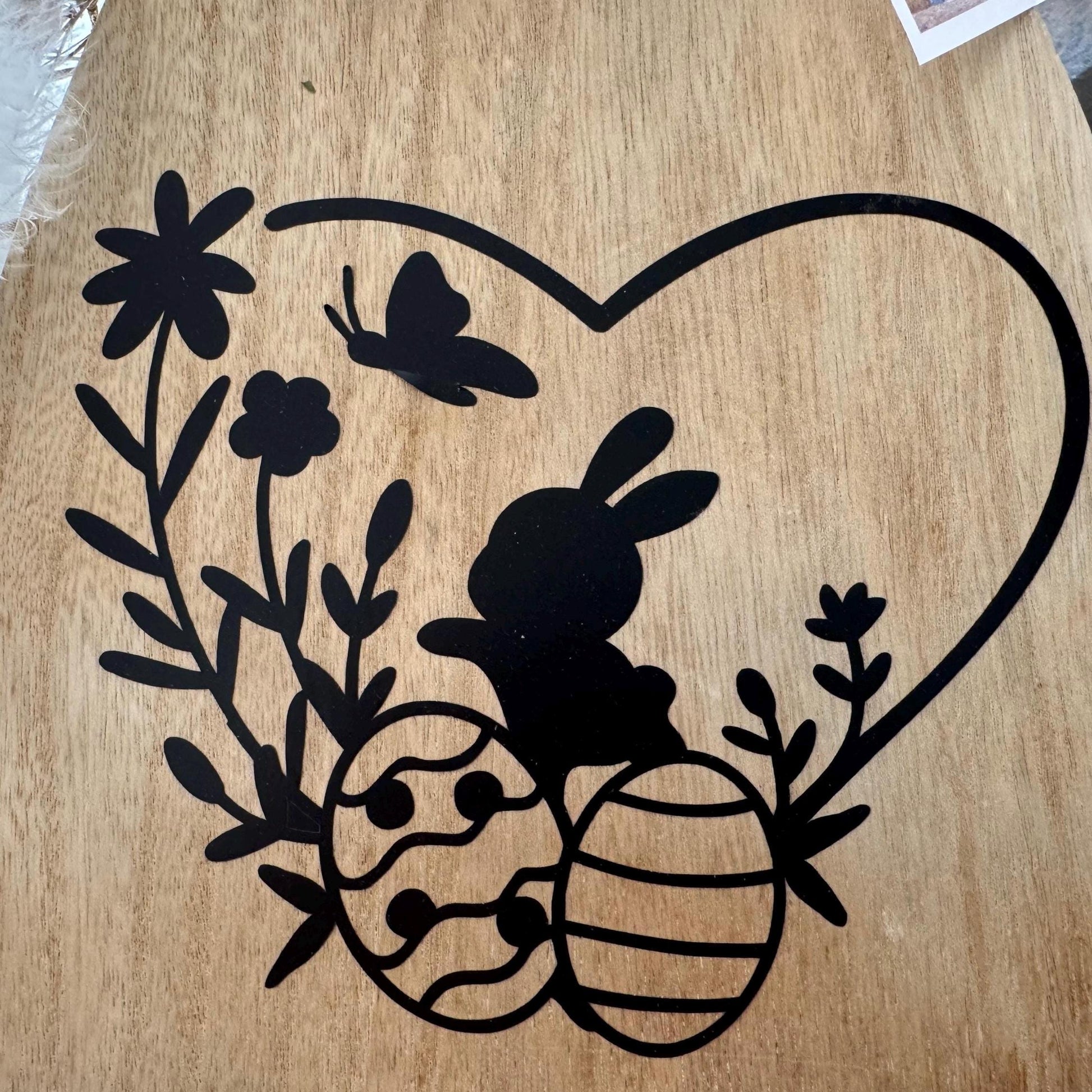 Detailaufnahme des schwarzen Hasen- und Osterei-Motivs auf dem hölzernen Osterhasen