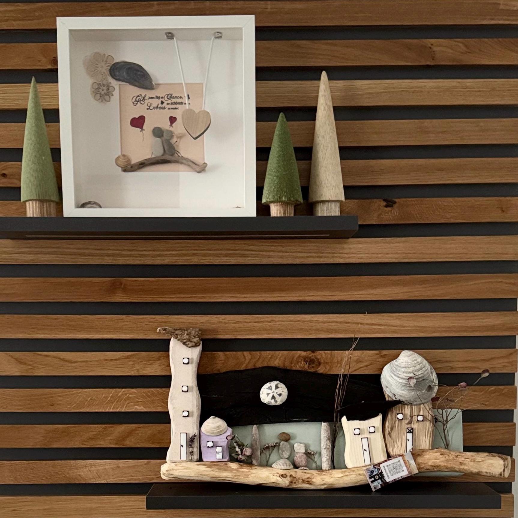 Steinbild im weißen Rahmen auf Holzregal vor Lamellenwand, nordische maritime Wanddekoration aus Naturmaterialien