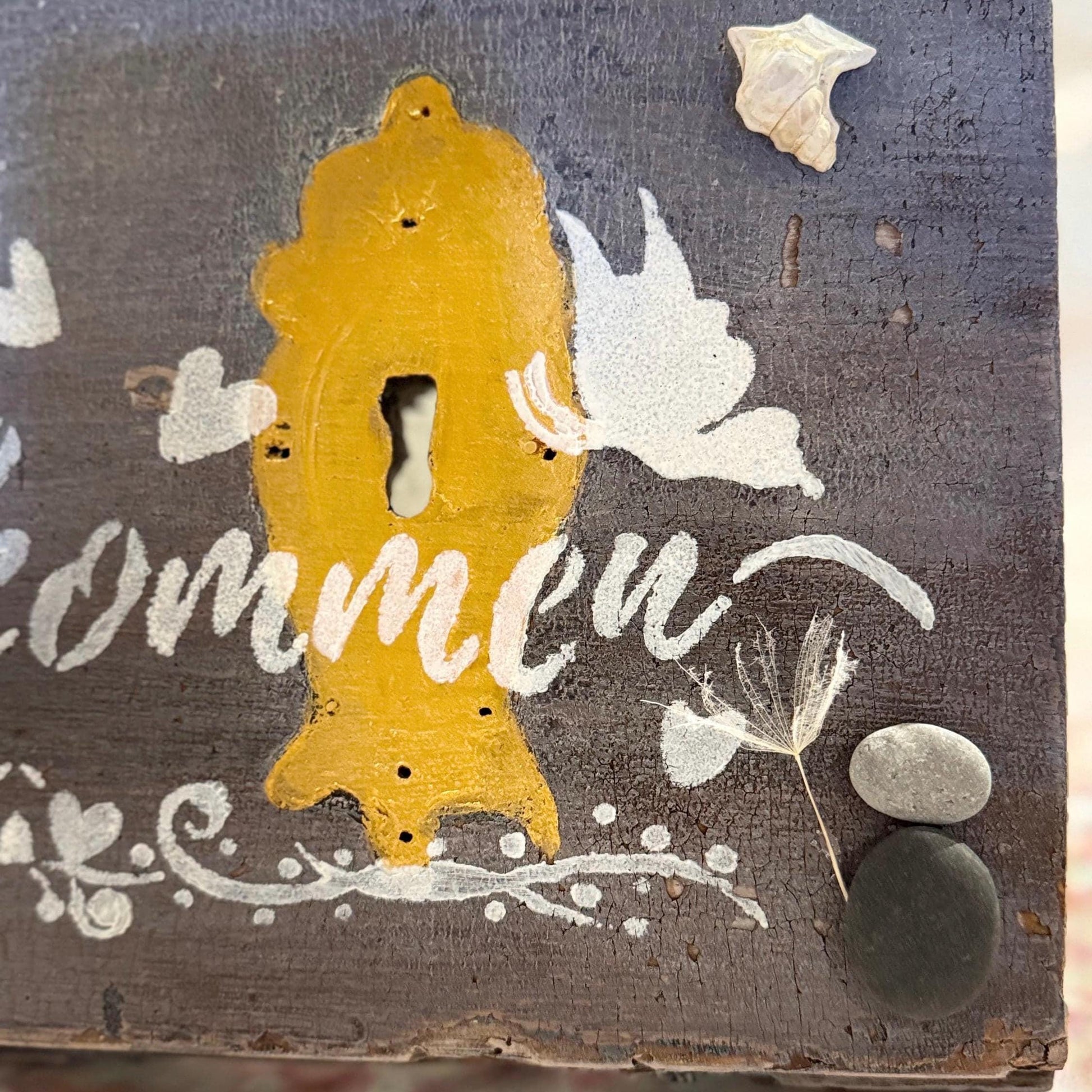 Ein rustikales Holzschild mit einem gelben Schlüsselloch-Design und dem Wort "willkommen" in weißer Schrift.