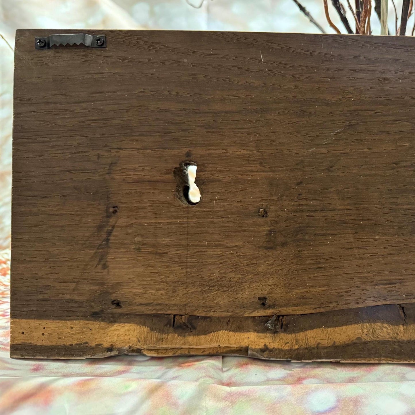 Rückseite eines rechteckigen Wanddekorationselements aus Holz. Das Holz ist dunkelbraun gebeizt, mit sichtbarer Maserung.