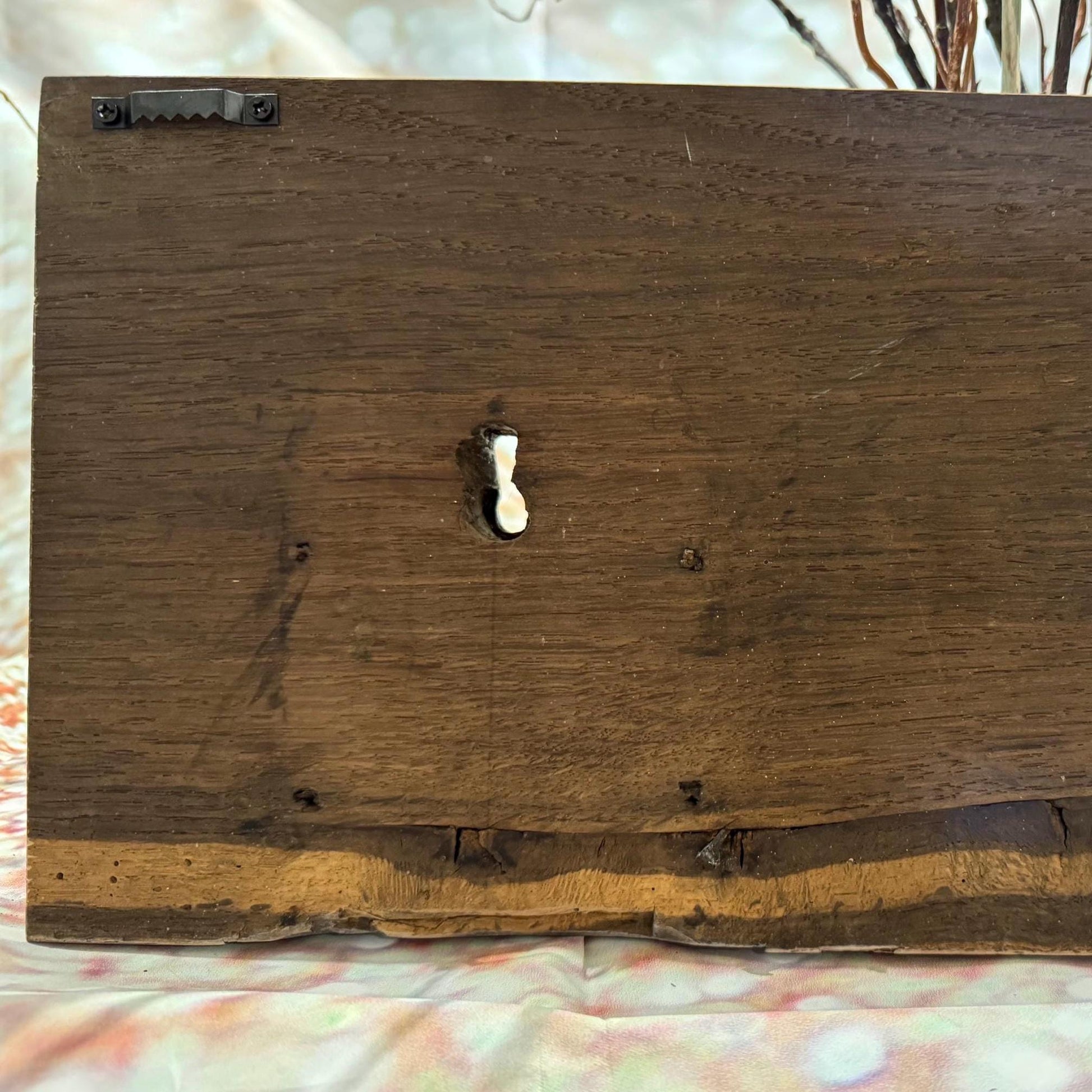 Rückseite eines rechteckigen Wanddekorationselements aus Holz. Das Holz ist dunkelbraun gebeizt, mit sichtbarer Maserung.