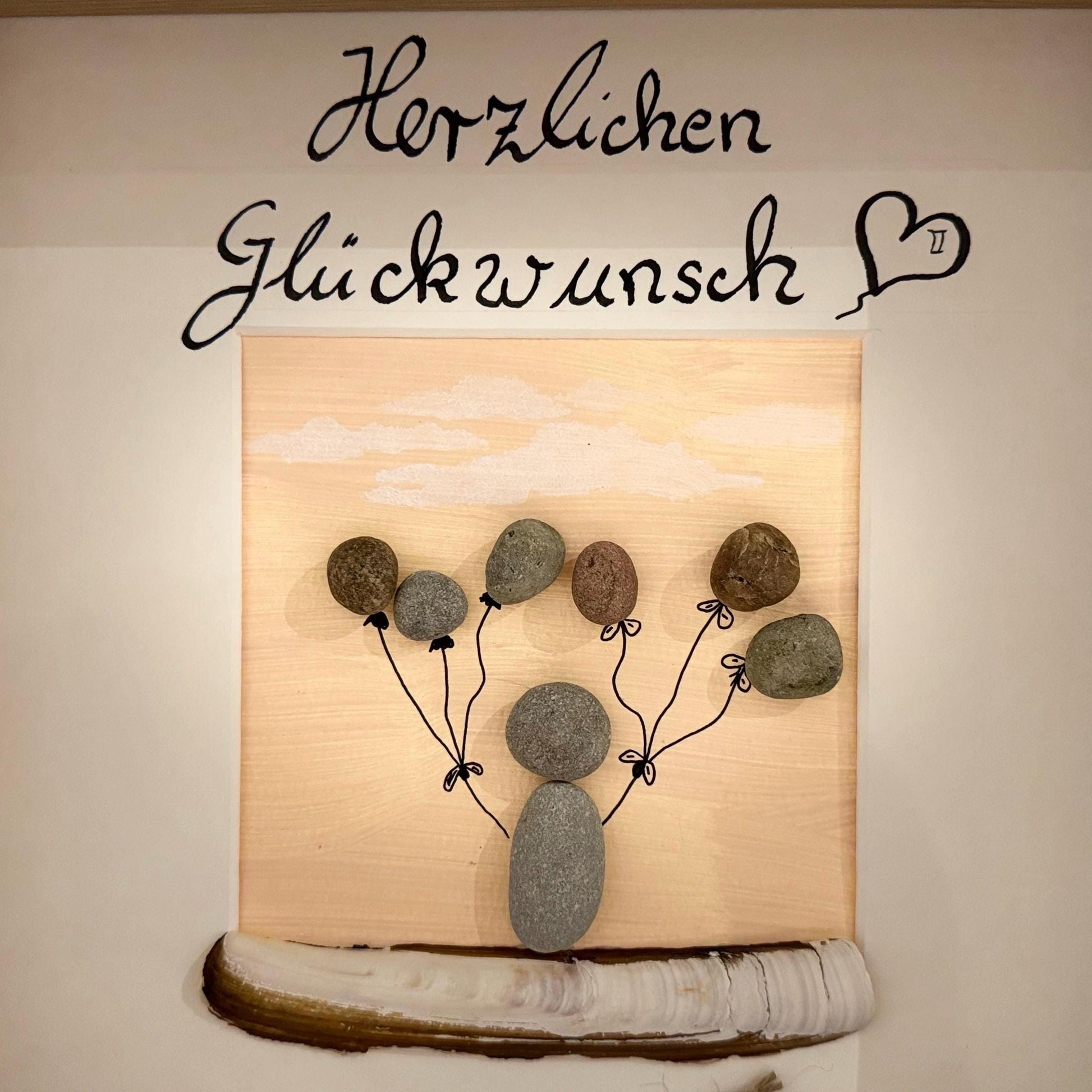 Handgefertigtes Kunstwerk mit einer Kieselperson, die Kieselballons hält von Treibholzzauber79