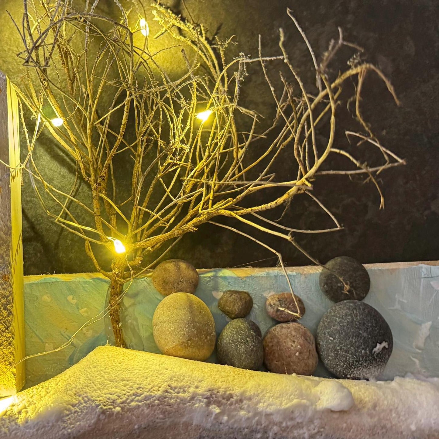 Ein rustikales Holzkunstwerk, das eine winterliche Dorflandschaft darstellt. Das Kunstwerk zeigt Miniaturhäuser.