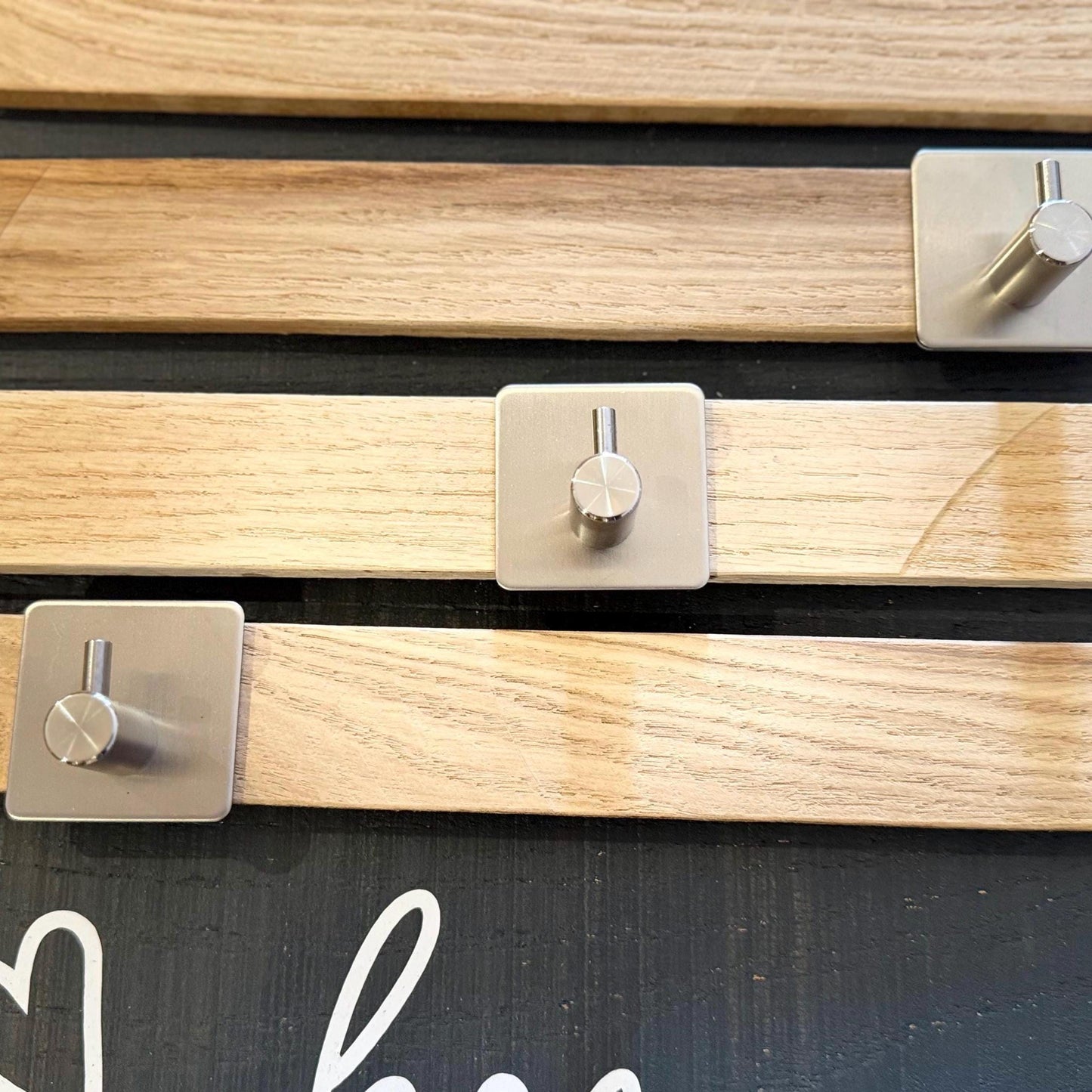 Nahaufnahme einer Wandpaneele aus Holz mit drei silbernen Metallhaken von Treibholzzauber79