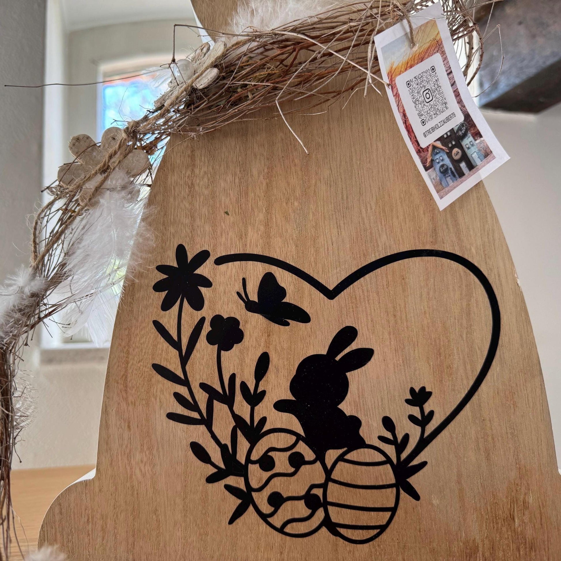 Seitliche Detailansicht des Osterhasen aus Holz mit Naturkranz, Federn und Anhänger von Treibholzzauber79