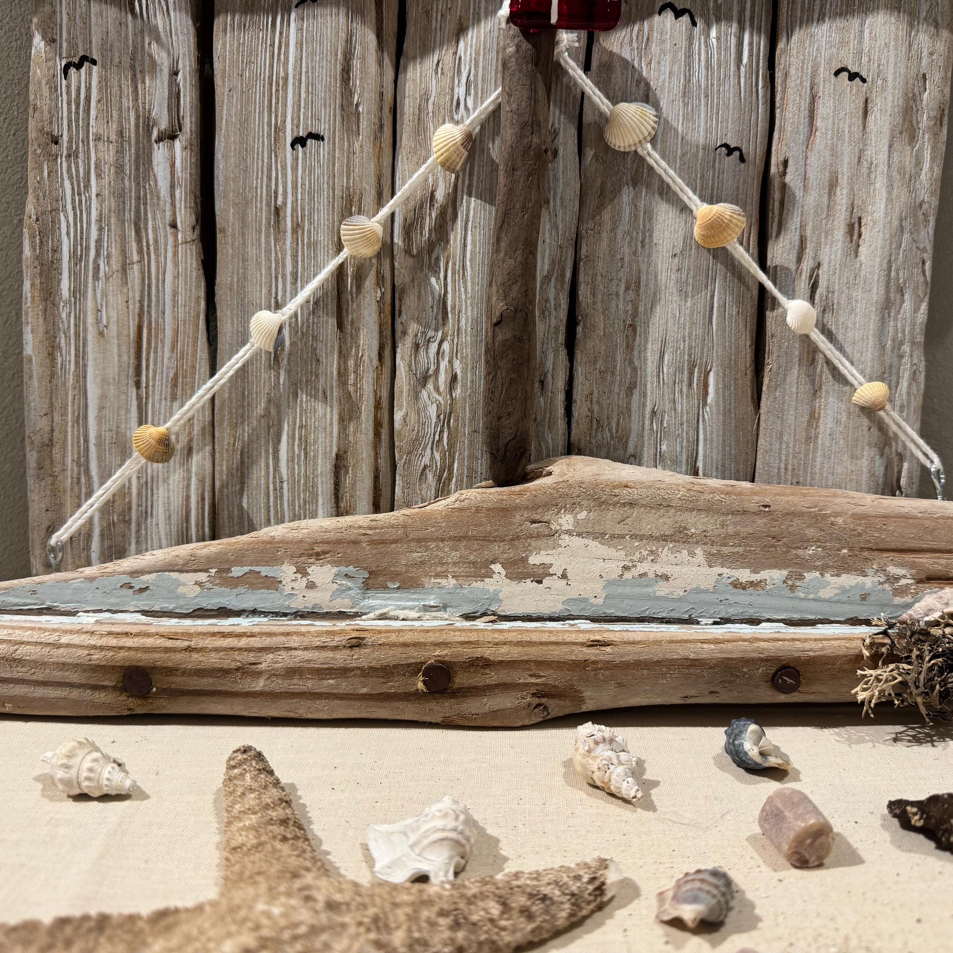 Nahaufnahme Wanddeko aus Treibholz in Naturtönen, maritim gestaltet mit kleinen Muscheln und Segelmotiv von Treibholzzauber79