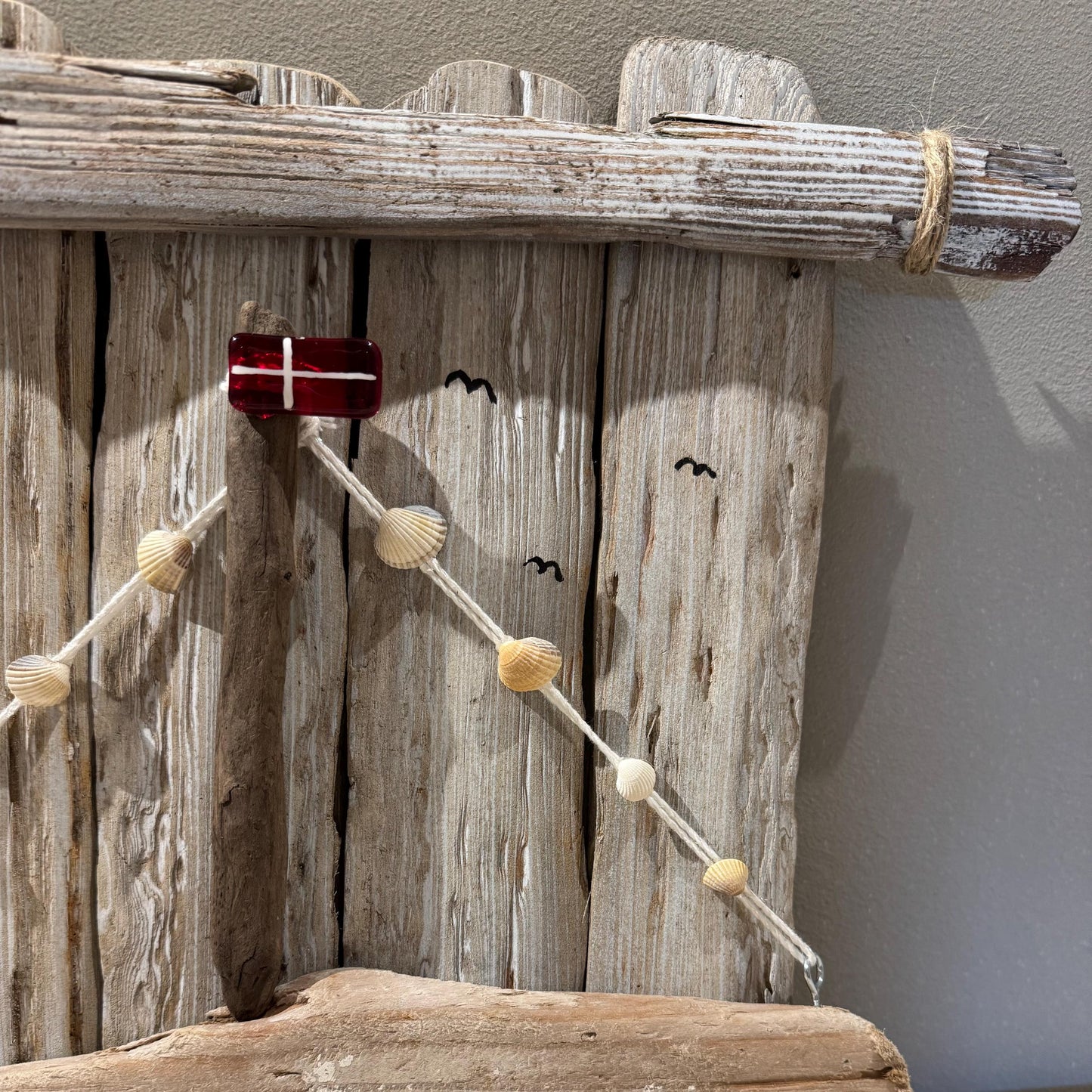 Nahaufnahme Wanddeko aus Treibholz in Naturtönen, maritim gestaltet mit kleiner Flagge und Segelmotiv von Treibholzzauber79