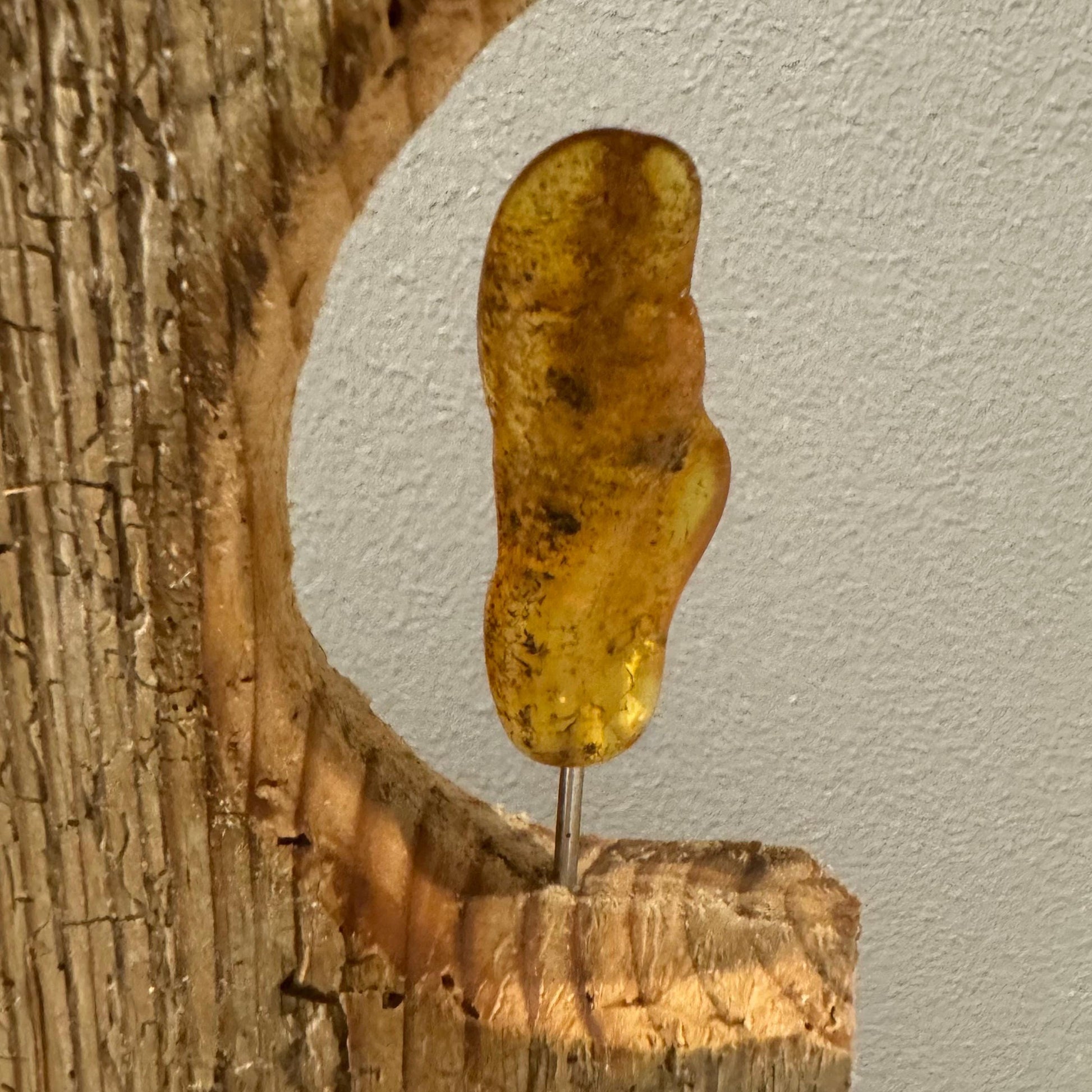Ein Stück Bernstein, ein durchscheinendes, goldgelbes versteinertes Harz, ist auf einem geschnitzten Holzsockel befestigt.