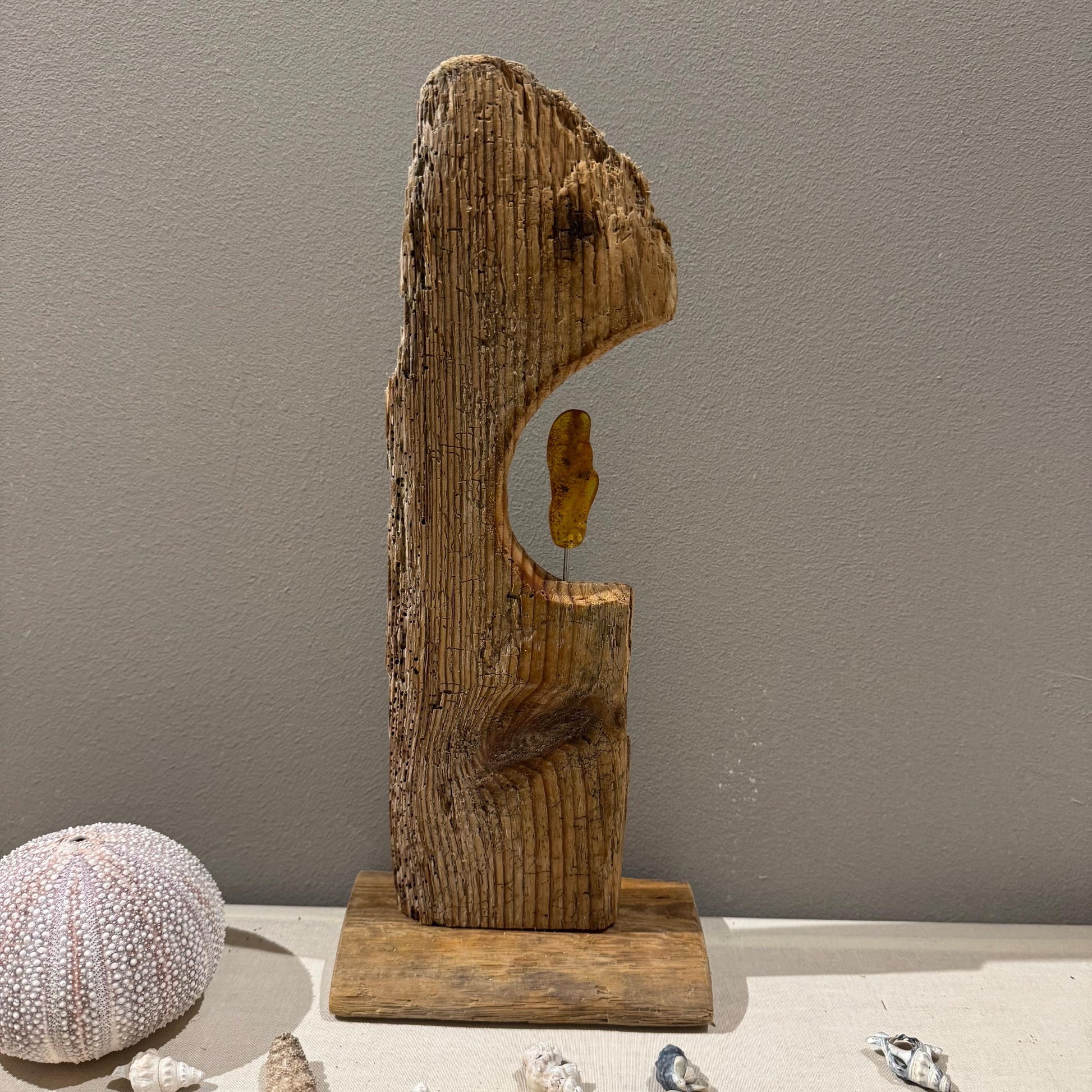 Eine rustikale Holzskulptur mit natürlicher, verwitterter Optik. Die Skulptur zeigt eine vertikale Holzplanke