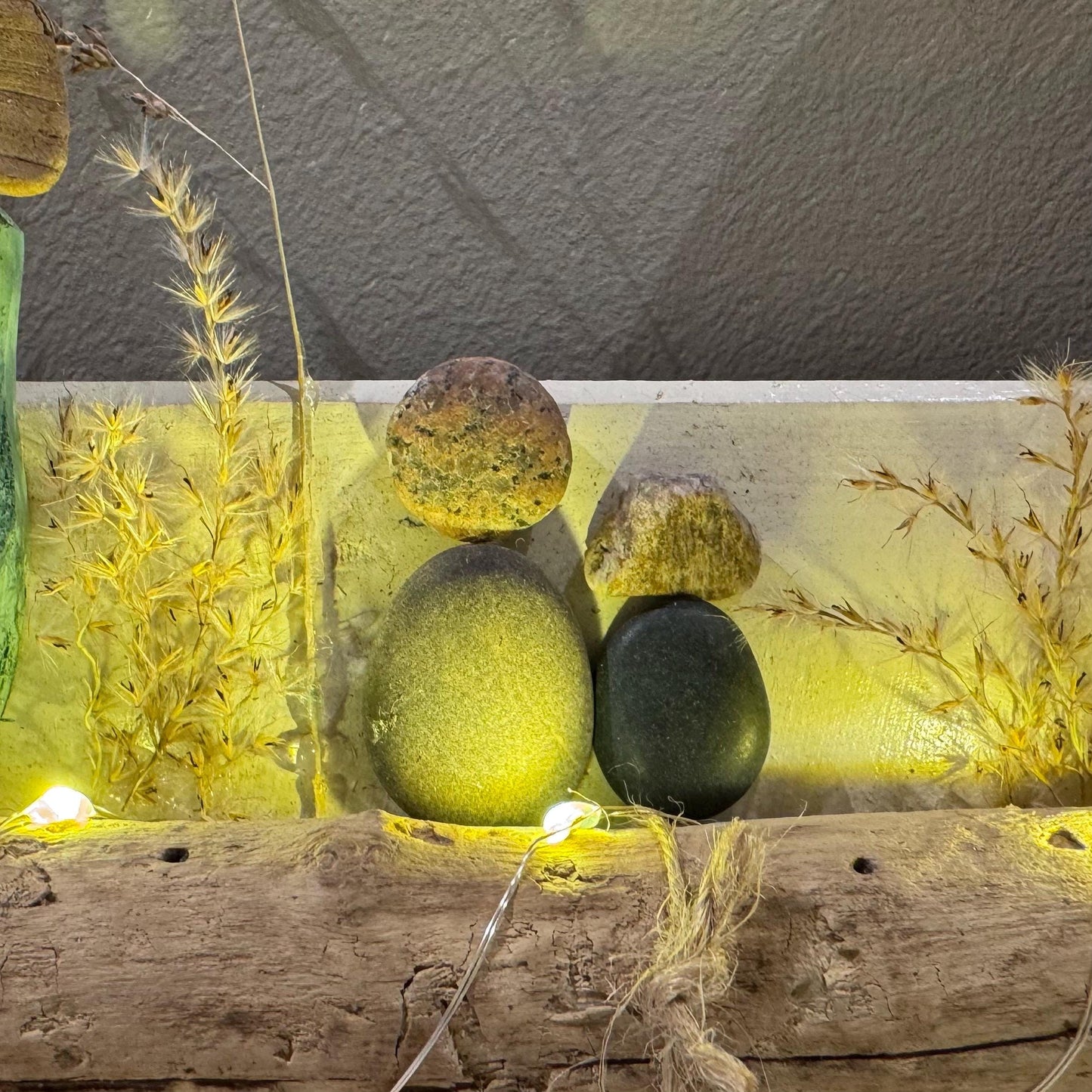 Treibholz Wanddeko Haus aus Treibholz mit kleinen Minihäusern und warmen LED-Lichtern auf heller Wand, maritime Dekoration.