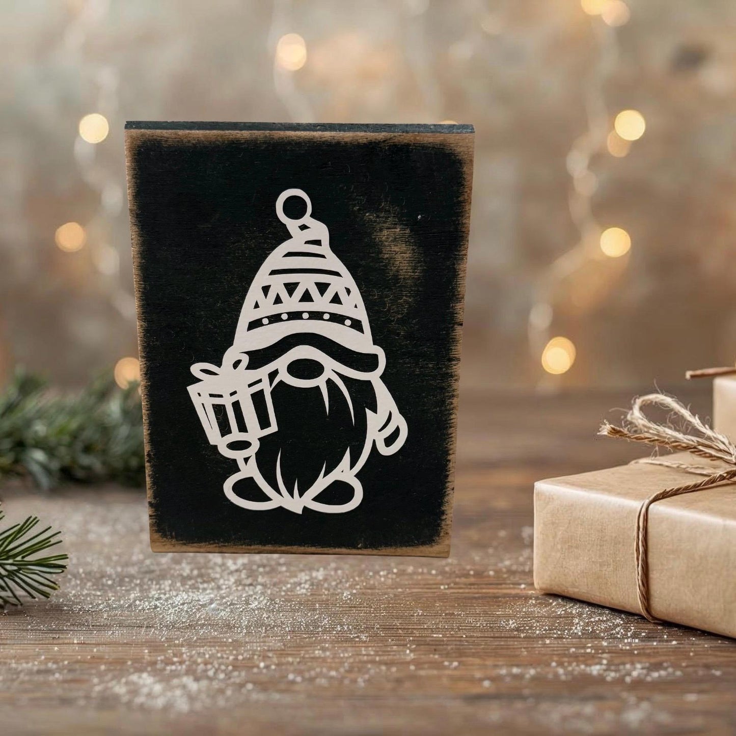 Rustikales Holzschild mit weißem Weihnachtswichtel-Motiv, dekoriert vor einem warmen, Hintergrund und natürlicher Winterdeko.