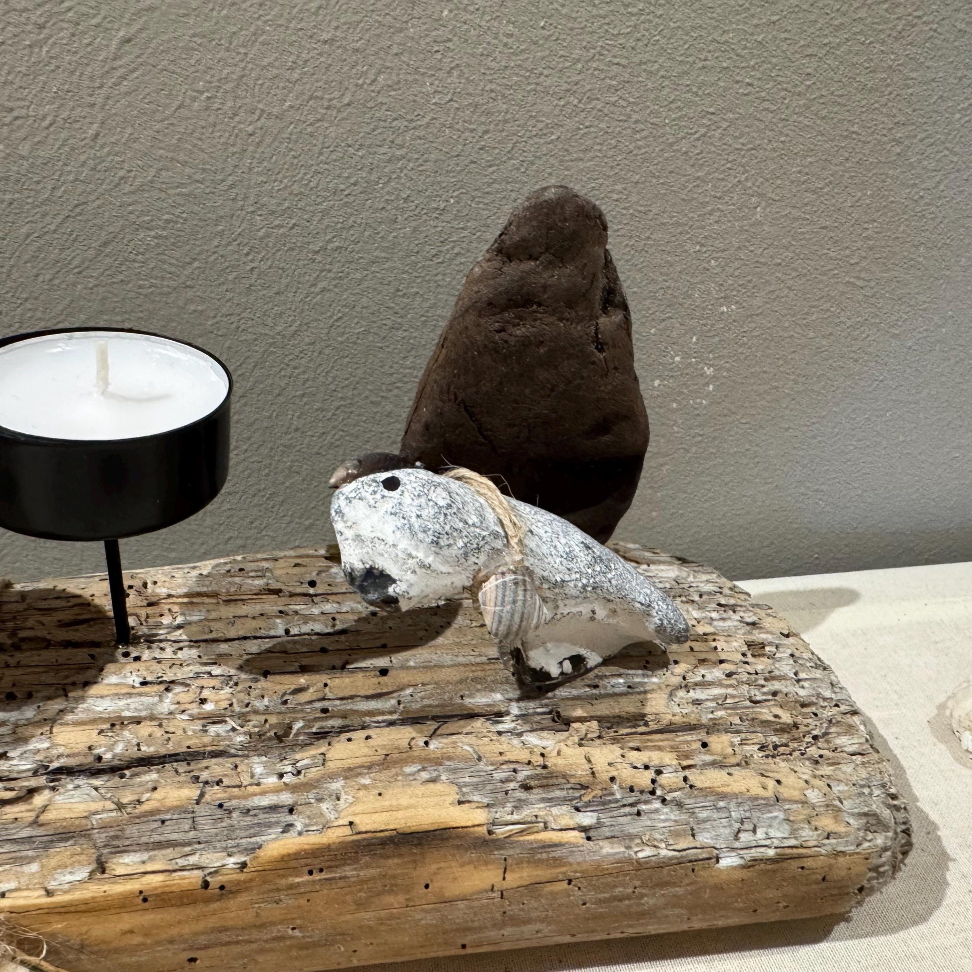 Teelichthalter aus Treibholz im Boho Style mit Steinfigur mit zwei schwarzen Metallkerzenhaltern. Küsten- und Naturthema.