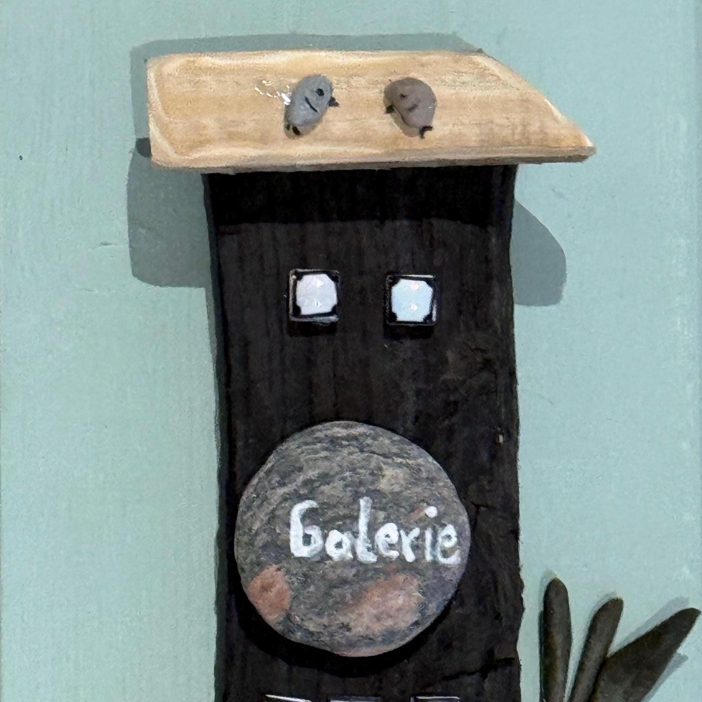 Handgemachte maritime Wandkunst mit schwarzem Haus und Steinaufschrift „Galerie“ aus Treibholz und Naturmaterialien.