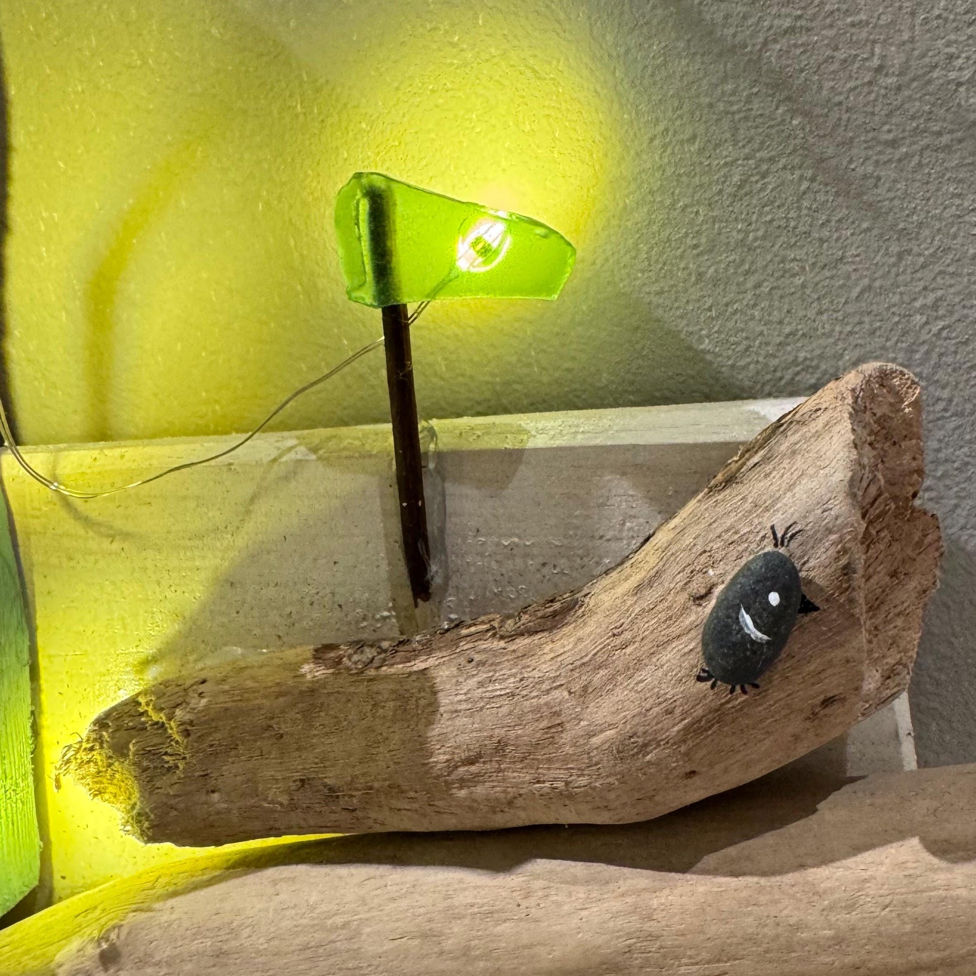 Treibholz Wanddeko Haus aus Treibholz mit kleinen Minihäusern und warmen LED-Lichtern auf heller Wand, maritime Dekoration.
