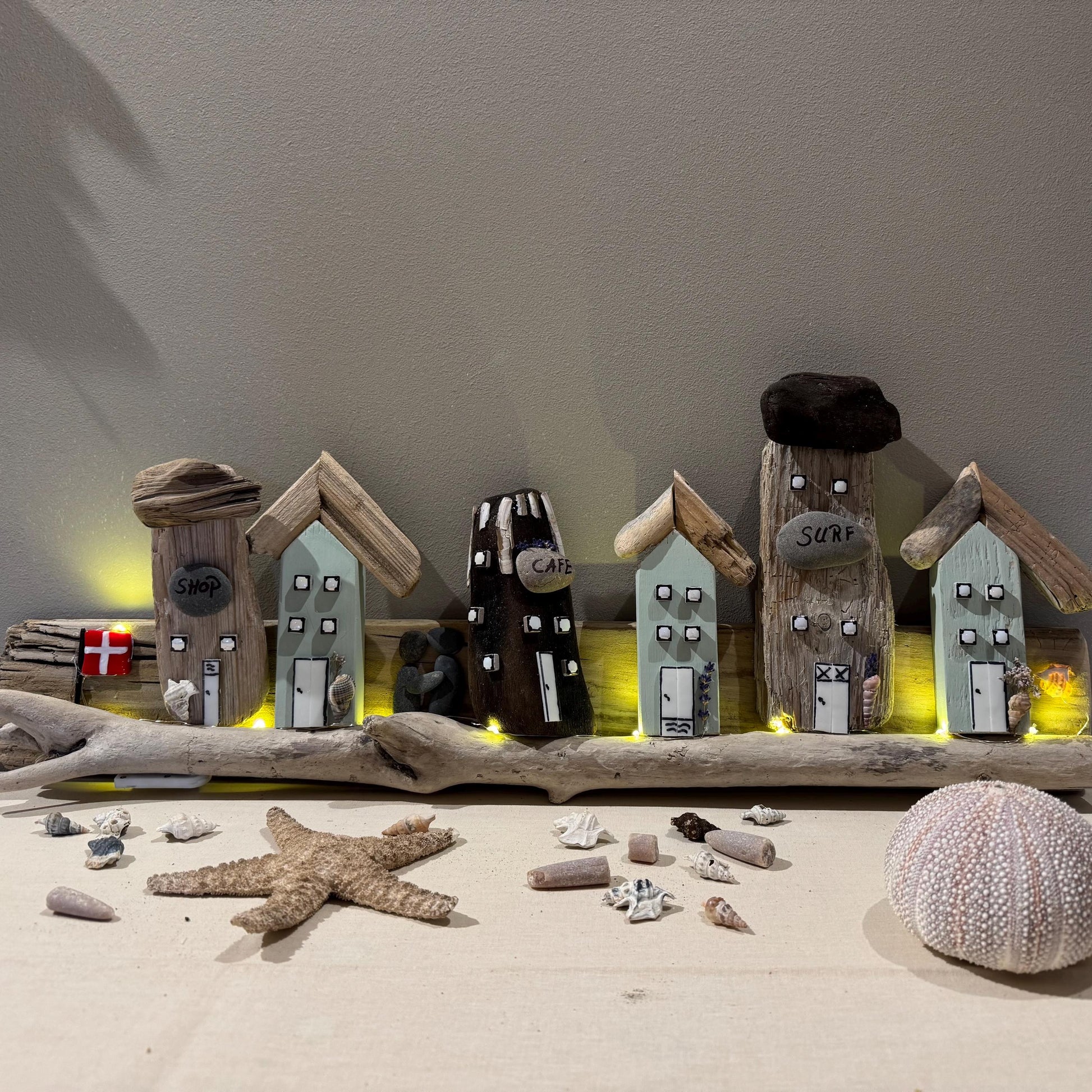 Handgemachtes Wandbild aus Treibholz – kleine Küstenhäuschen mit Café und Surfhaus, liebevoll dekoriert mit Naturmaterialien