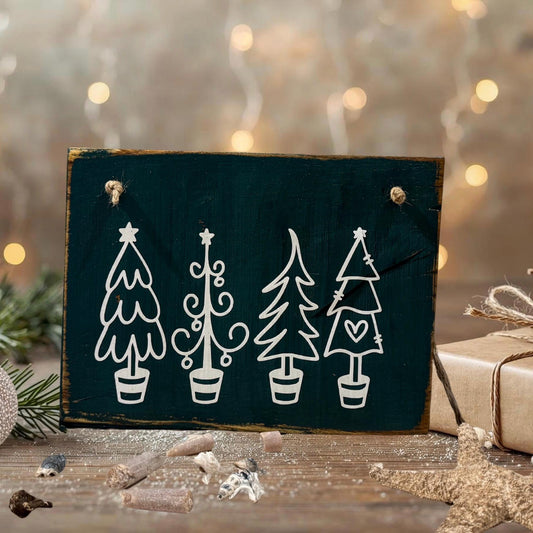 Handgemachte Weihnachts-Deko aus dunklem Holz mit vier weißen, stilisierten Tannenbäumen im Topf – minimalistisch, nordisch und winterlich dekoriert.