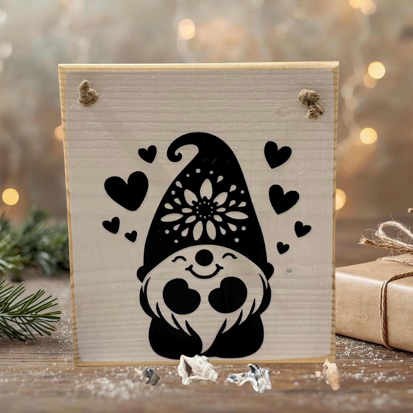 Ein Holzschild mit einem schwarzen Zwerg-Design, das ein lächelndes Gesicht, einen floralen Hut und Herzen zeigt.