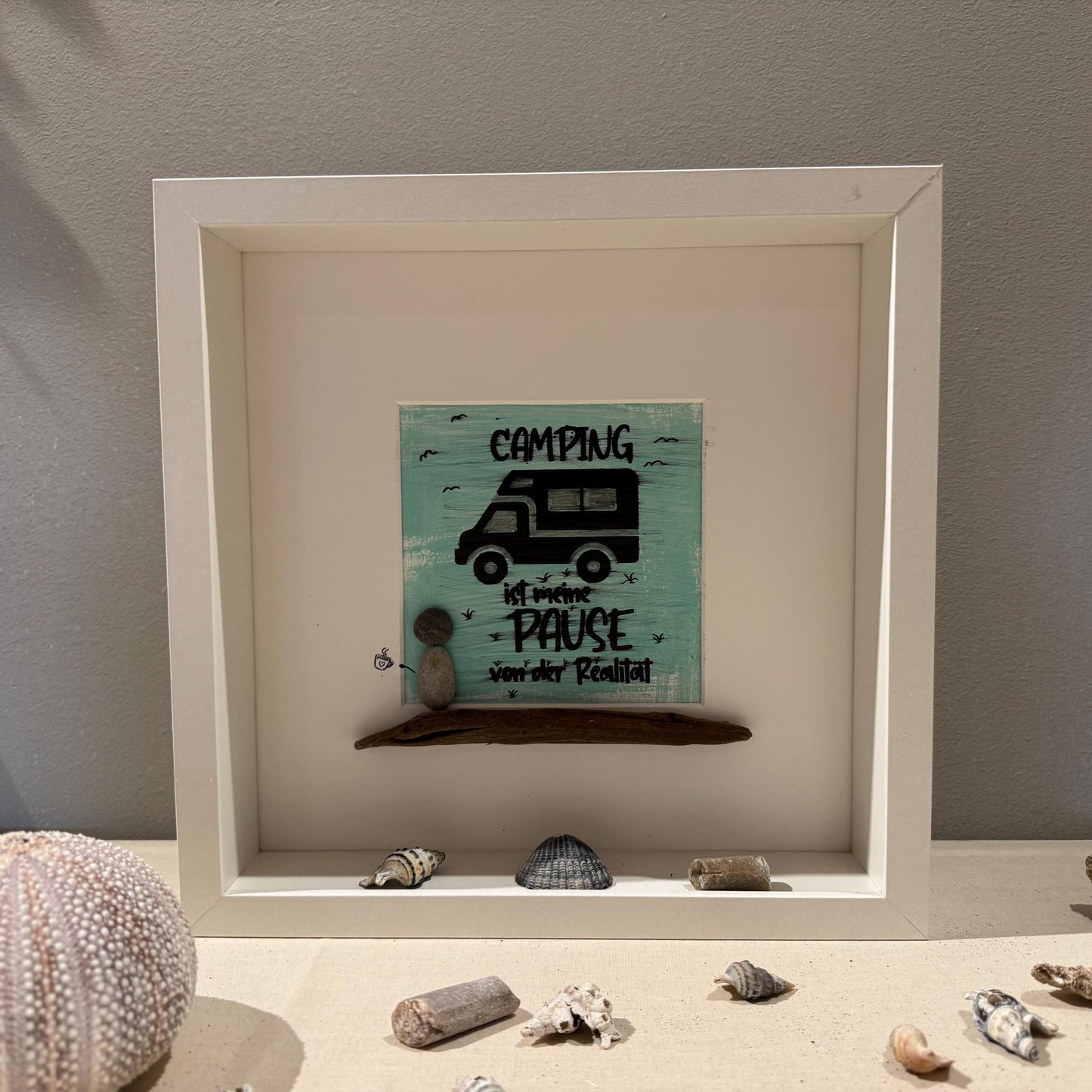 Das Kunstwerk zeigt einen türkisfarbenen Hintergrund mit einer Wohnmobil-Illustration und dem Wort "CAMPING"