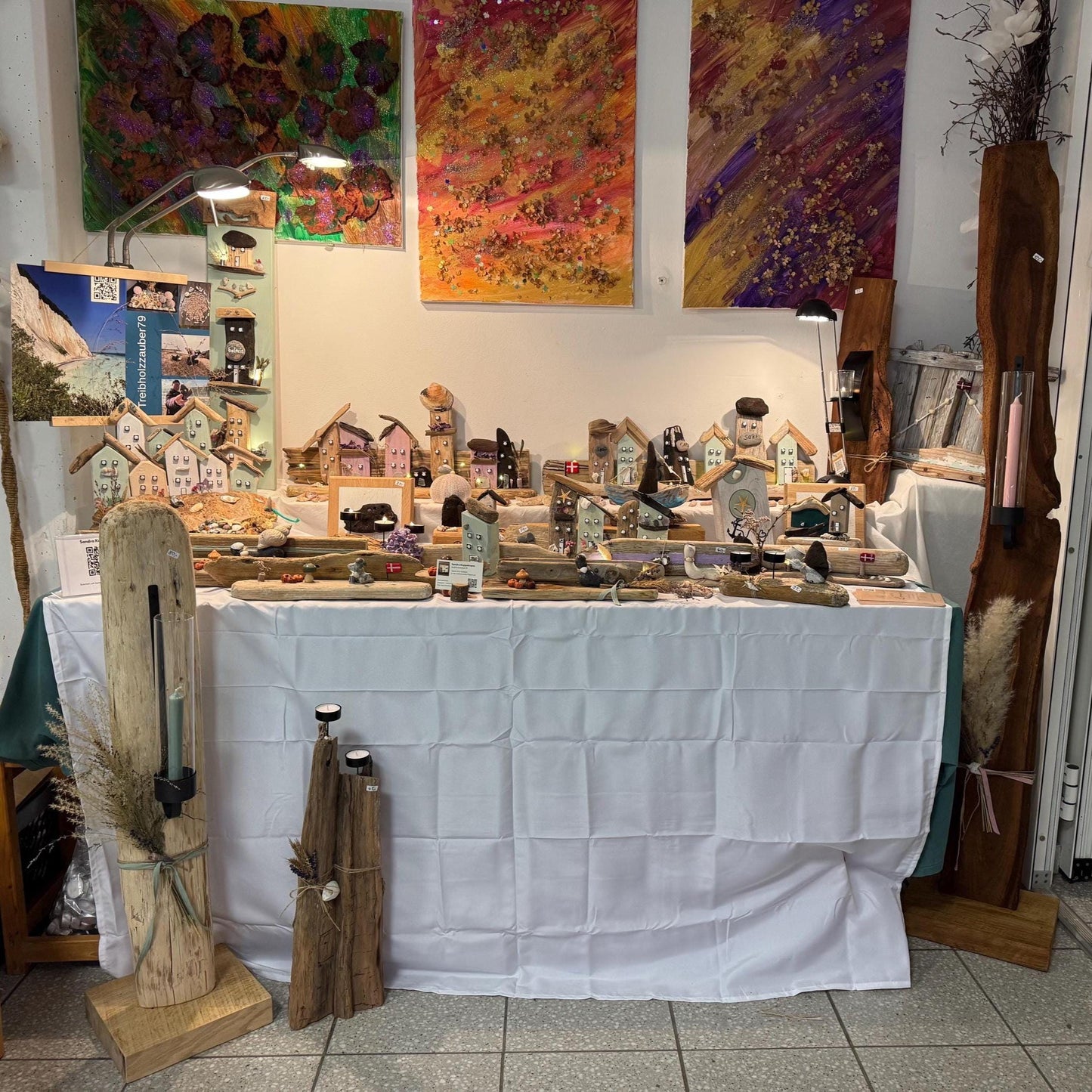 Ein Stand mit handgefertigten Holzhäusern in verschiedenen Farben und Designs von Treibholzzauber79