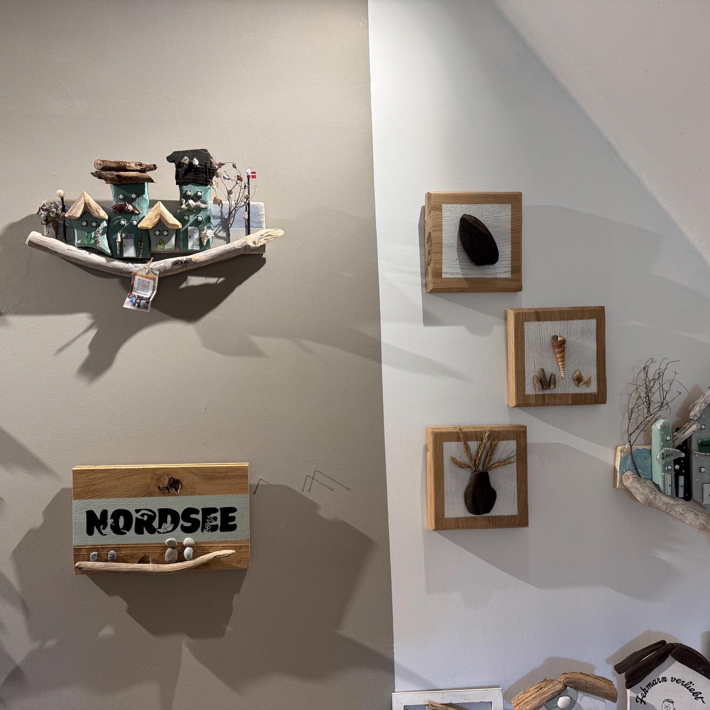 Holzkunst für die Wand mit Miniaturhäusern mit grünen und braunen Dächern, montiert auf einem Treibholzsockel.
