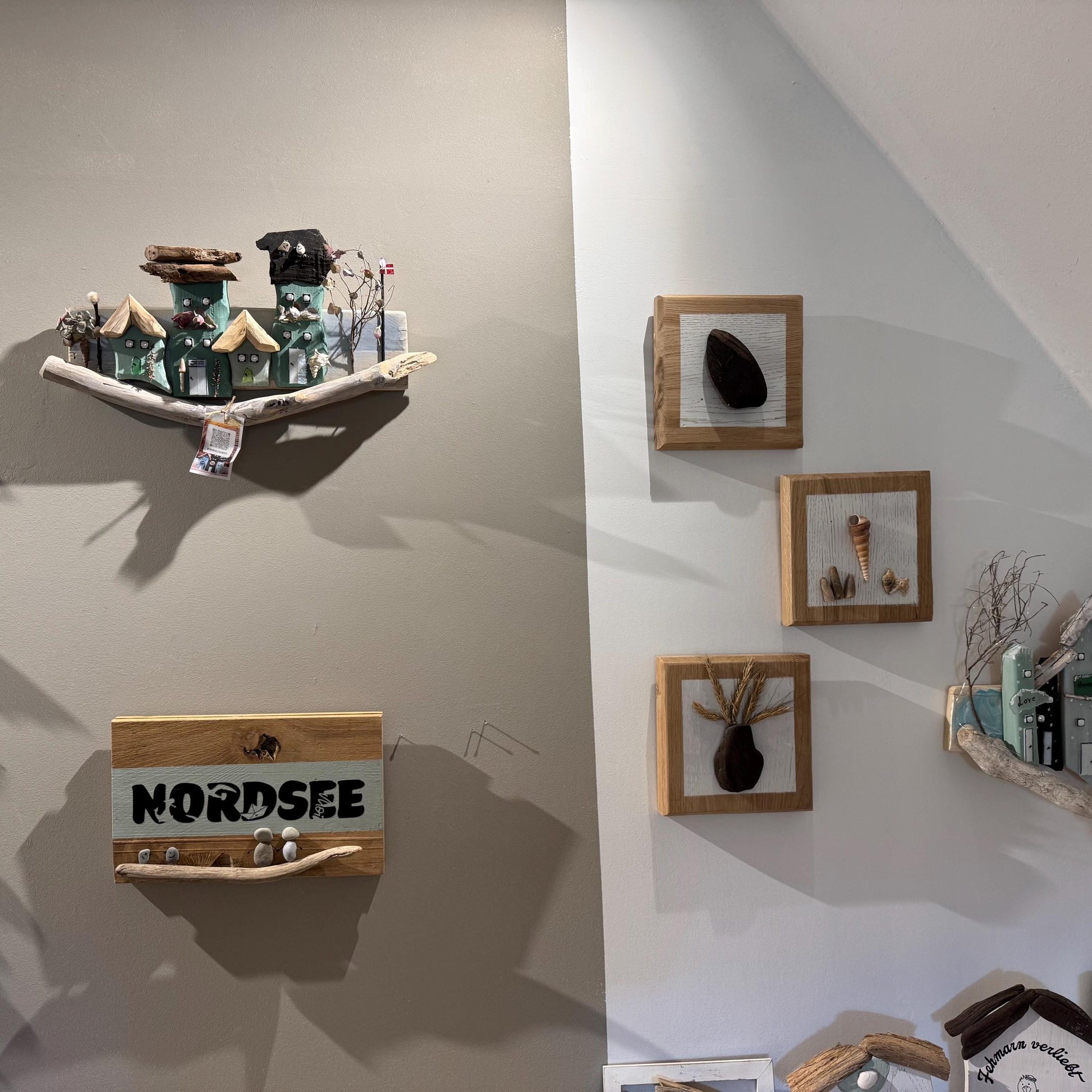 Holzkunst für die Wand mit Miniaturhäusern mit grünen und braunen Dächern, montiert auf einem Treibholzsockel.