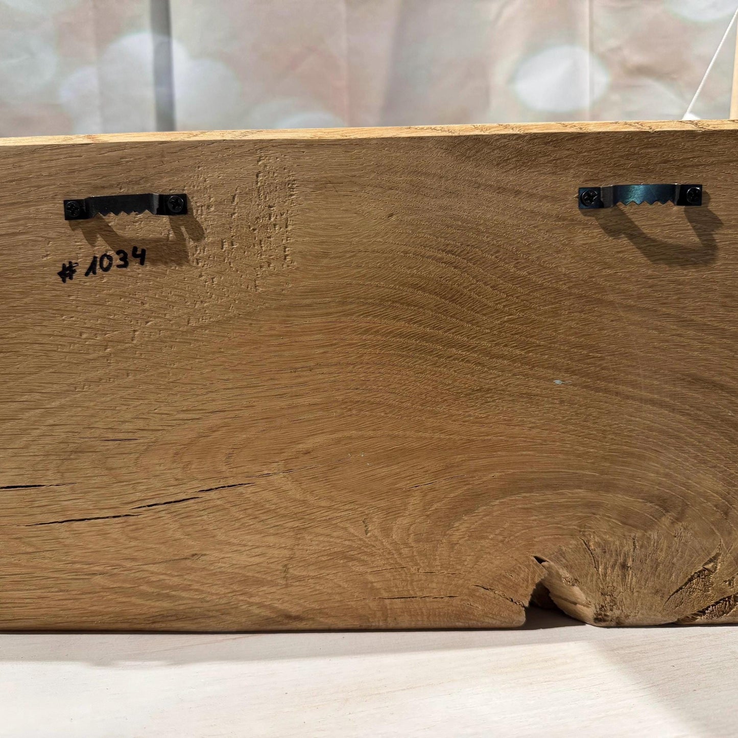 Nahaufnahme der Rückseite eines Holz-Kunstwerks. Die natürliche Holzmaserung ist sichtbar. Zwei Aufhänger sind angebracht.