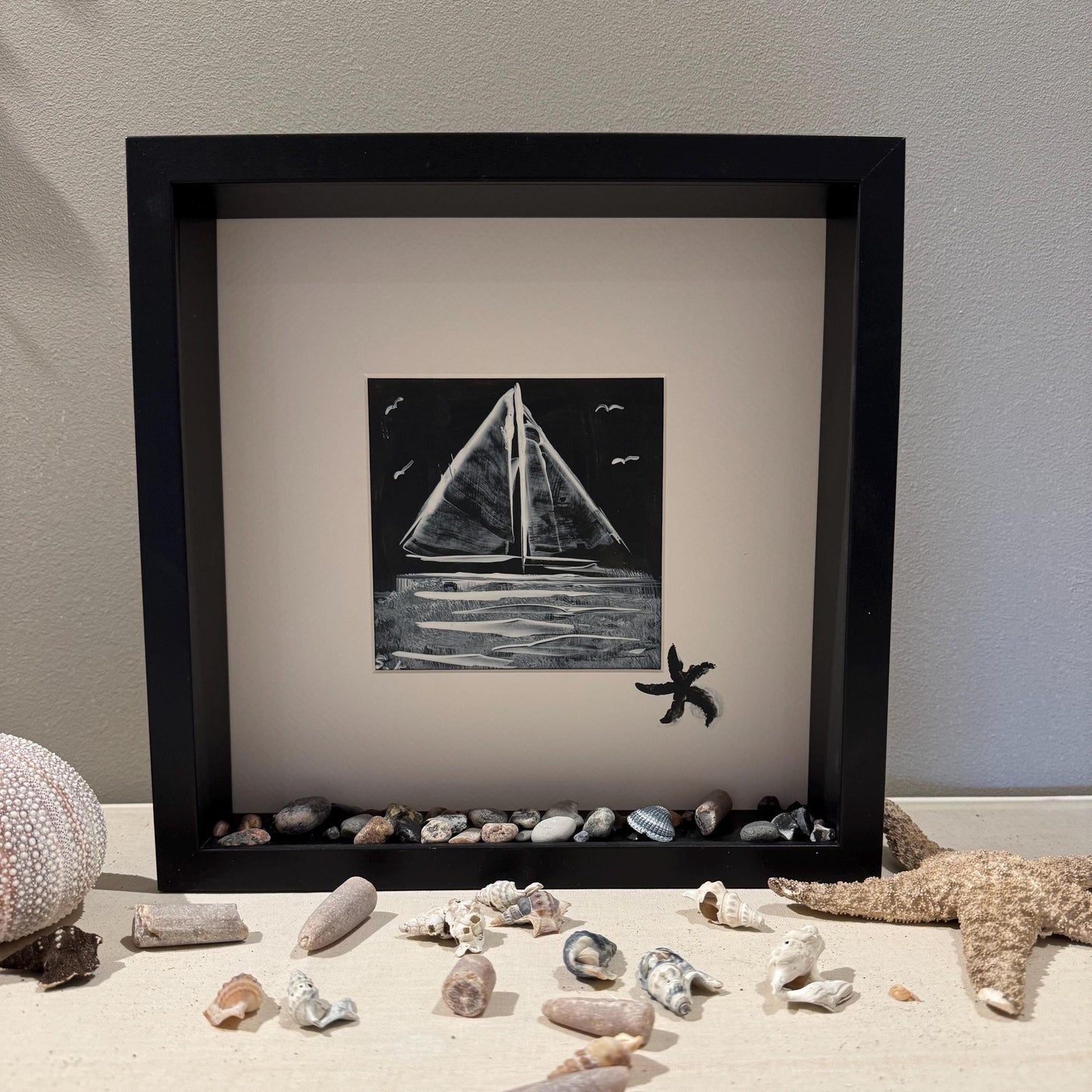 Ein gerahmtes Kunstwerk mit schwarzem Rahmen, das eine Segelboot-Illustration in Weiß auf schwarzem Hintergrund zeigt
