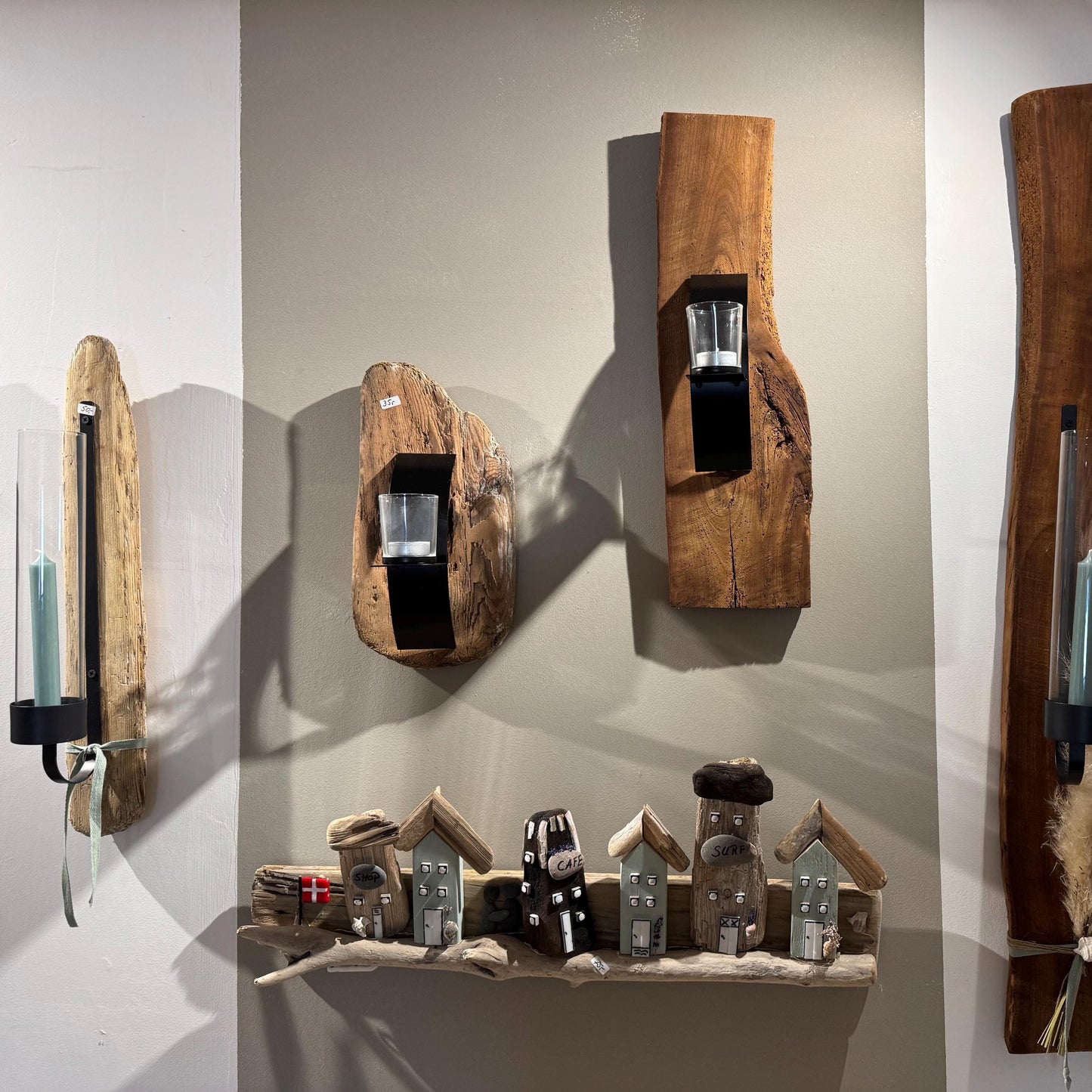 Holzwanddekoration mit Kerzenhaltern und Miniaturhausfiguren. Die Kerzenhalter sind aus Naturholz gefertigt