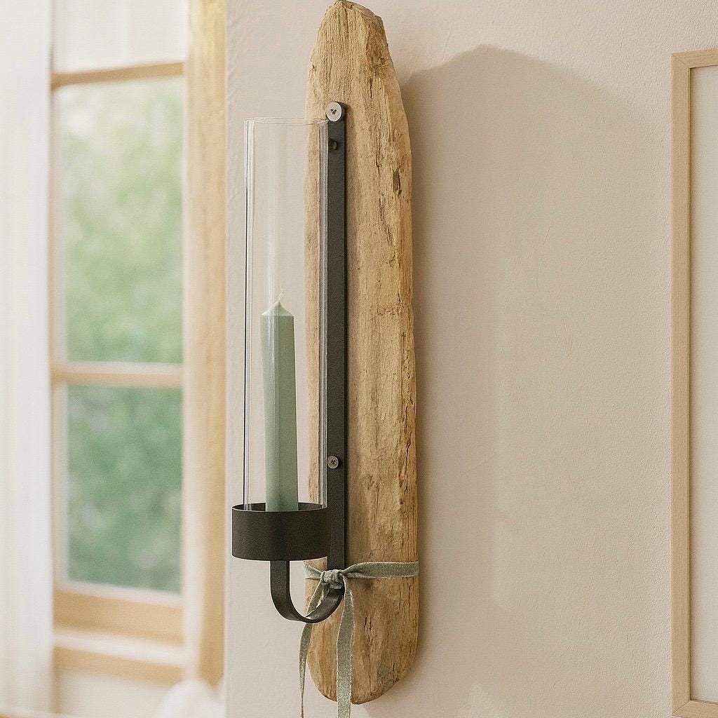 Ein Wandkerzenhalter mit einem Naturholzsockel und einem dunklen Metallrahmen. Ein klarer Glaszylinder hält eine Kerze.