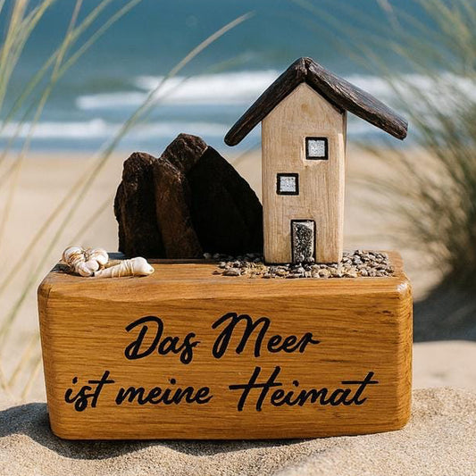 Maritime Deko "Das Meer ist meine Heimat" mit kleinem Treibholzhaus im Sand zwischen Dünen und Blick aufs Meer.