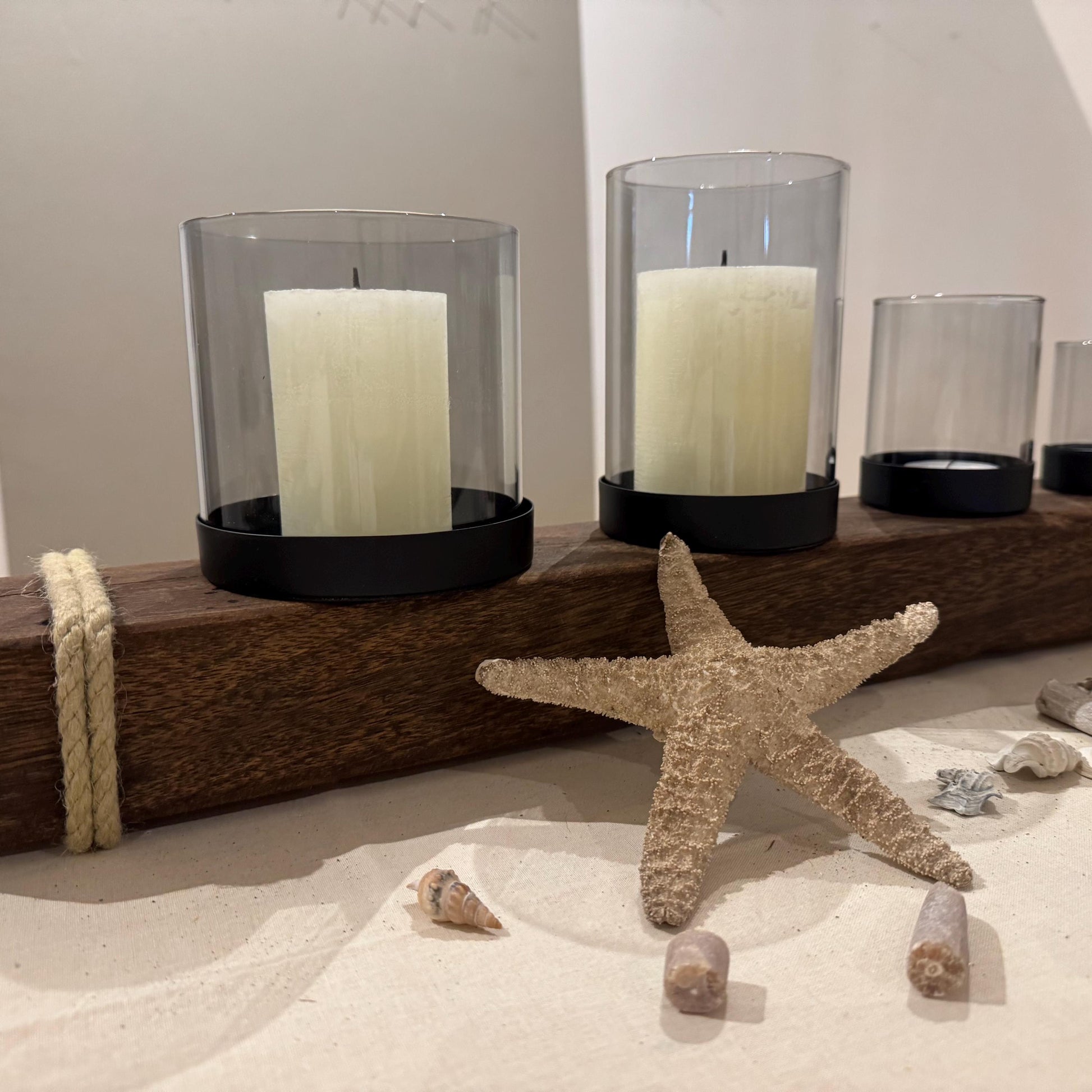 Ein hölzerner Kerzenhalter mit drei Glas-Windlichtern und weißen Kerzen von Treibholzzauber79