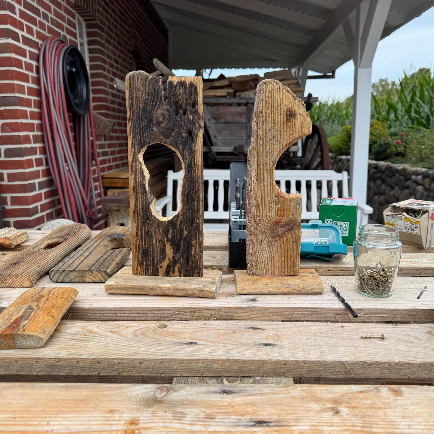 Zwei rustikale Holzskulpturen mit einzigartigen Ausschnitten, die auf kleinen Holzsockeln stehen.