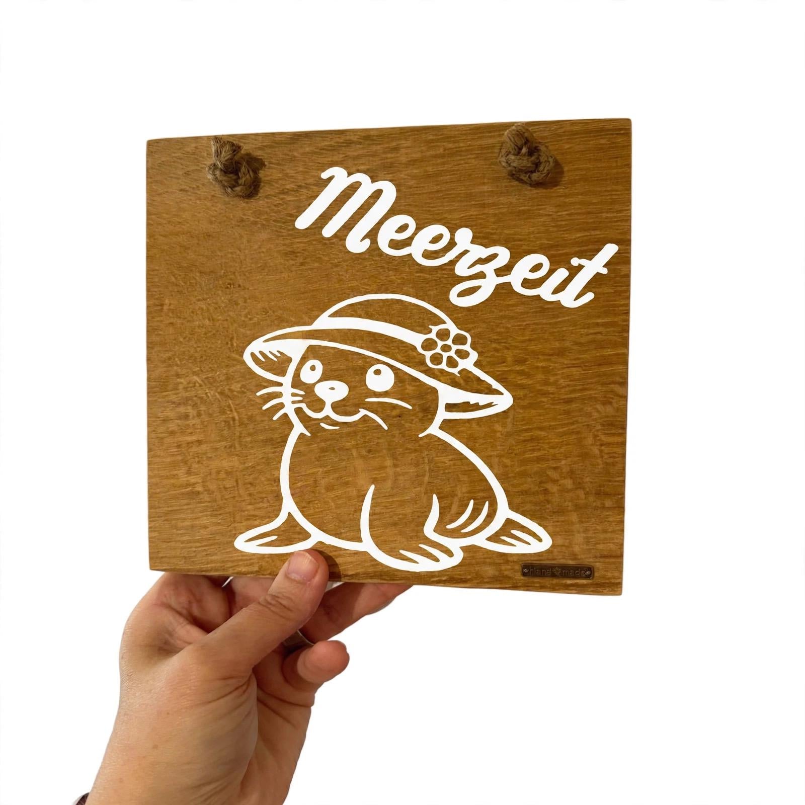 Hand hält kleines Holzschild Meerzeit 20cm Eiche – handtellergroßes Deko Schild mit Robbe Mila Milo & Mila Serie handmade