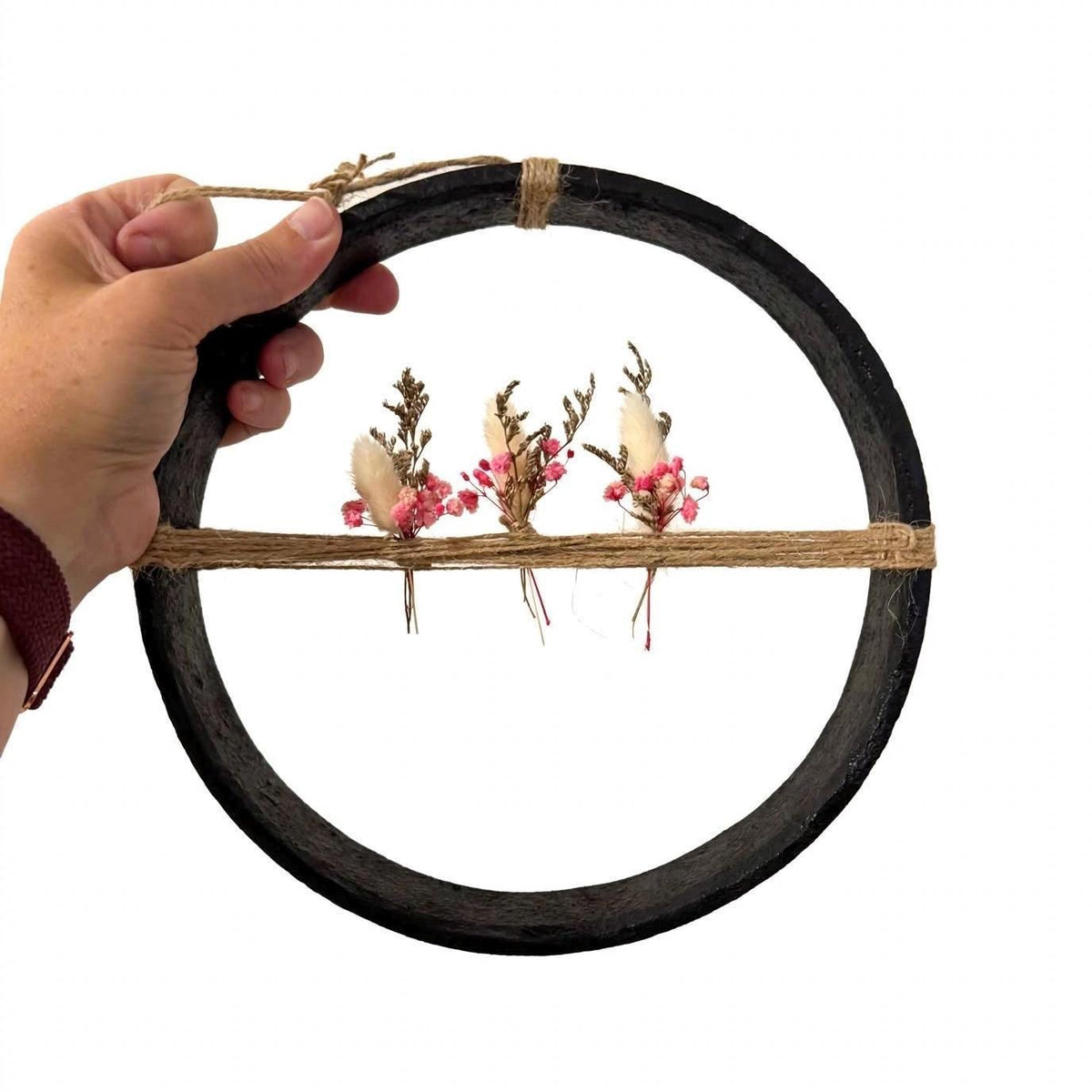 Eisenring Deko 24cm in der Hand gehalten, zeigt Größe des Wagenrad Kranz mit rosa Trockenblumen, Größenvergleich